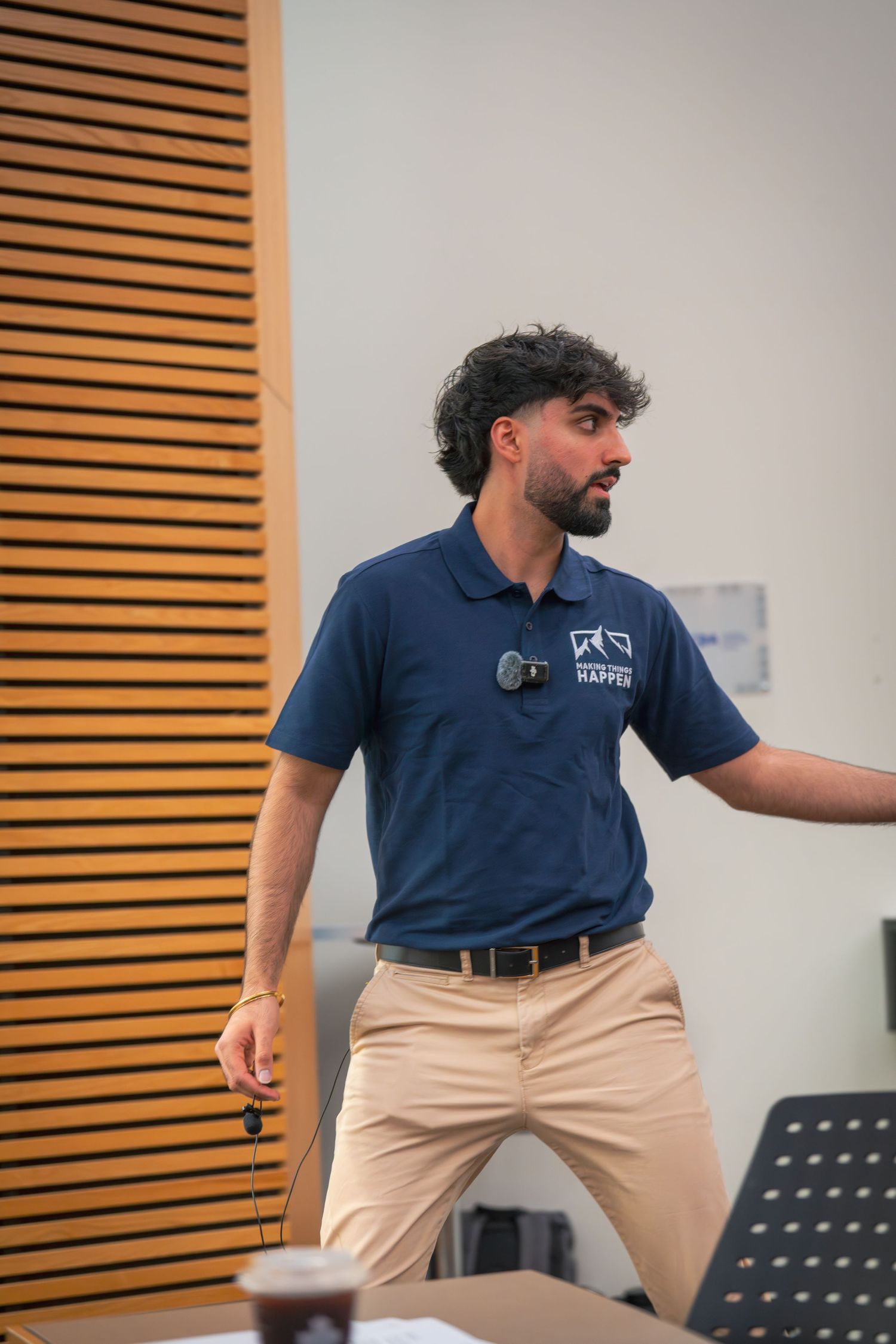 A person in a navy blue uniform demonstrates animated body language while presenting.