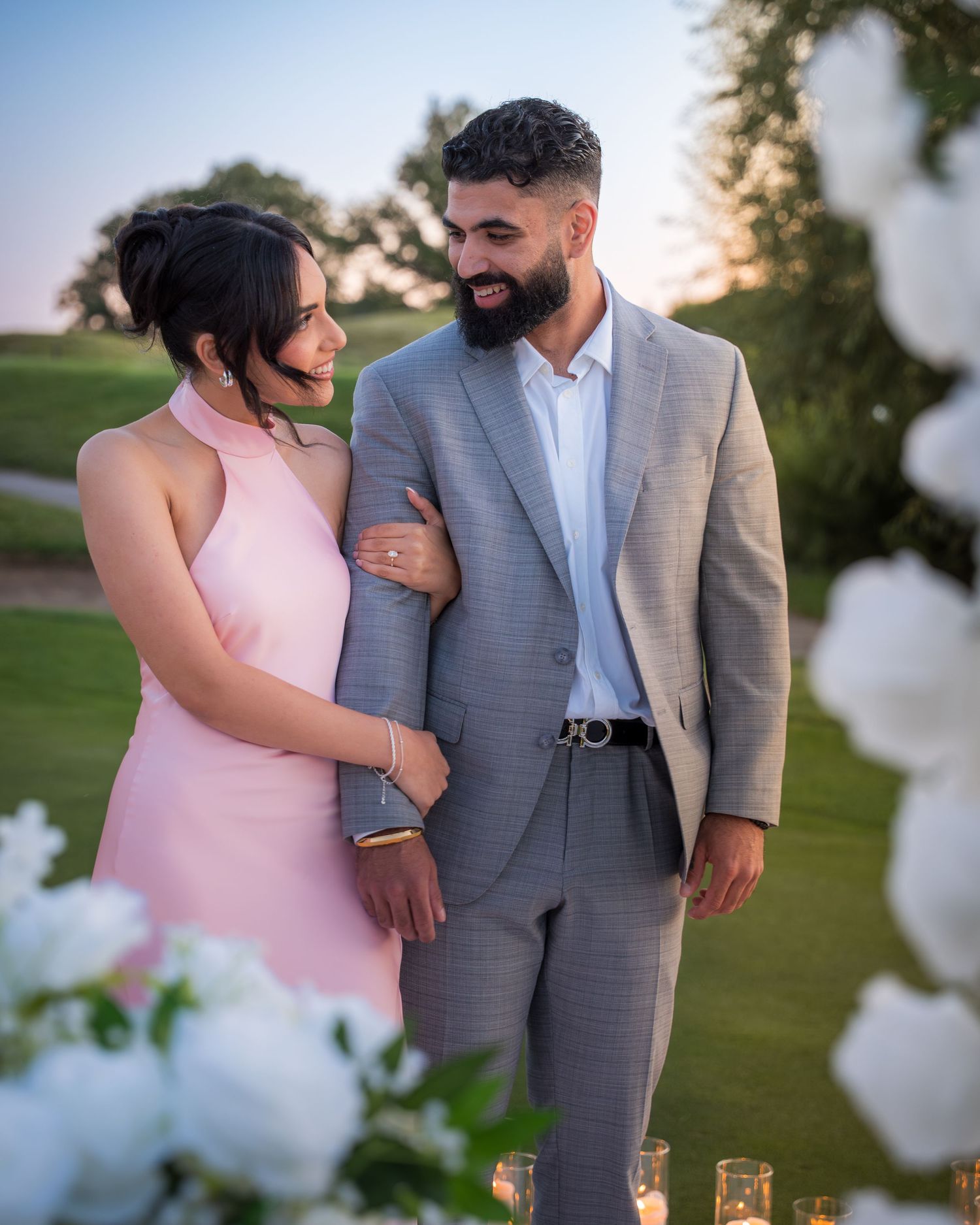 Couple shares tender moments during sunset photoshoot with white floral decor.