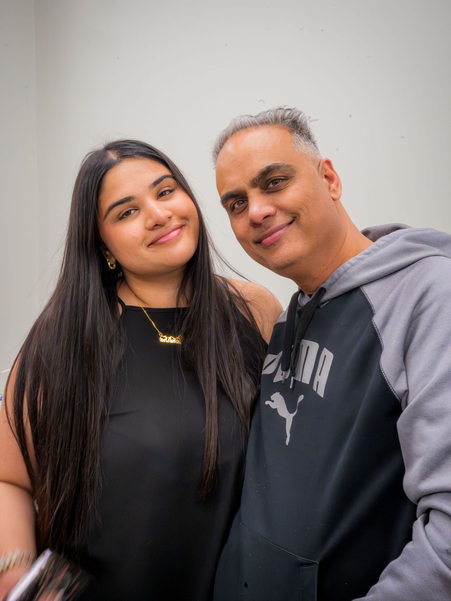 A young woman and older man with gray hair smile together for a portrait photo.