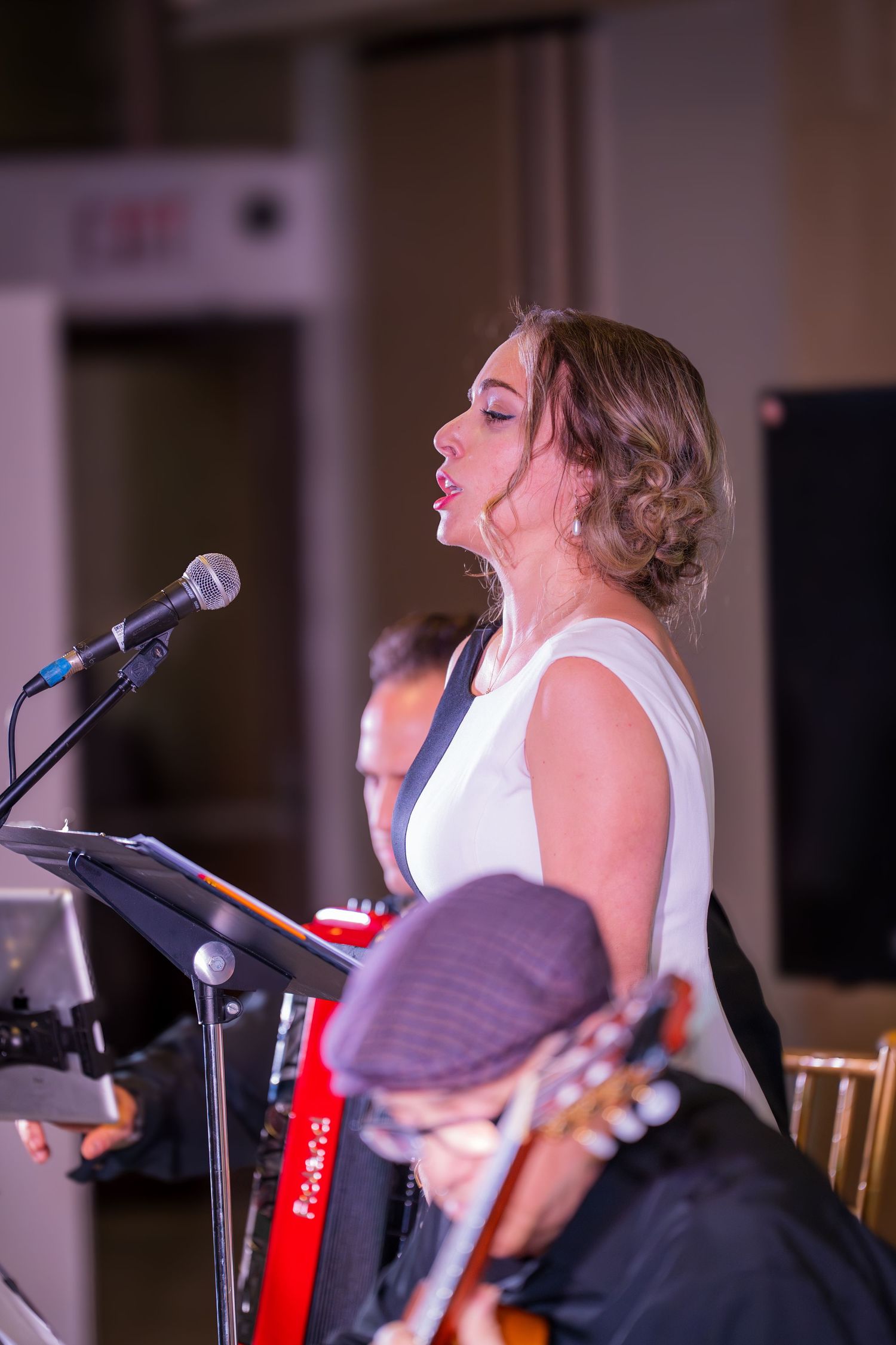 A female vocalist sings passionately at a microphone with a guitarist visible in the foreground.