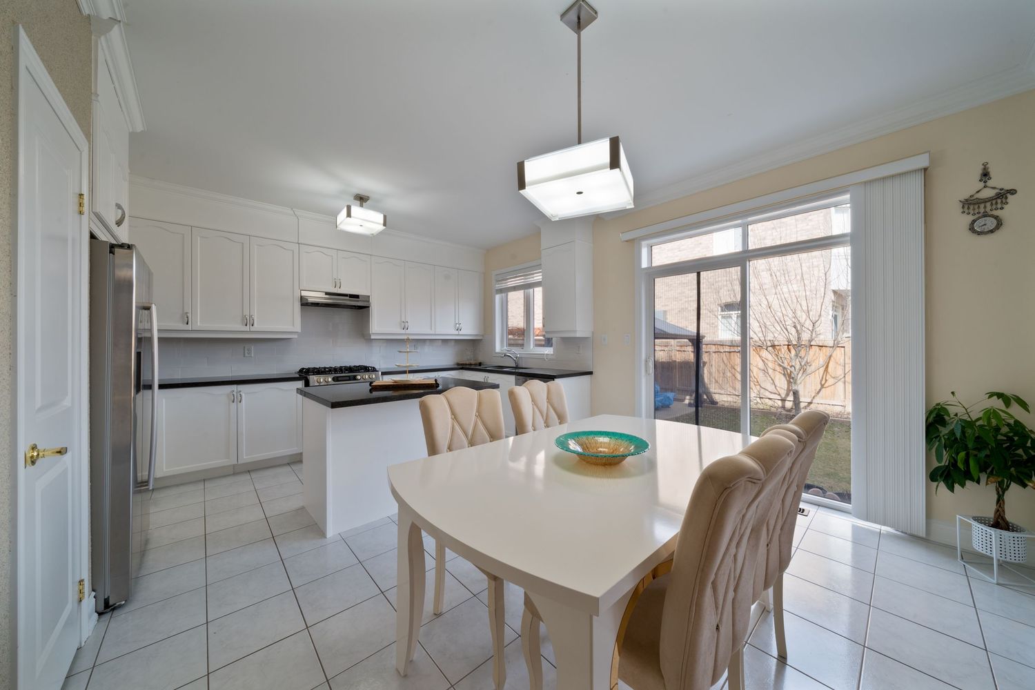 Modern white kitchen interior with light wood cabinets, stainless steel appliances and bright natural lighting.
