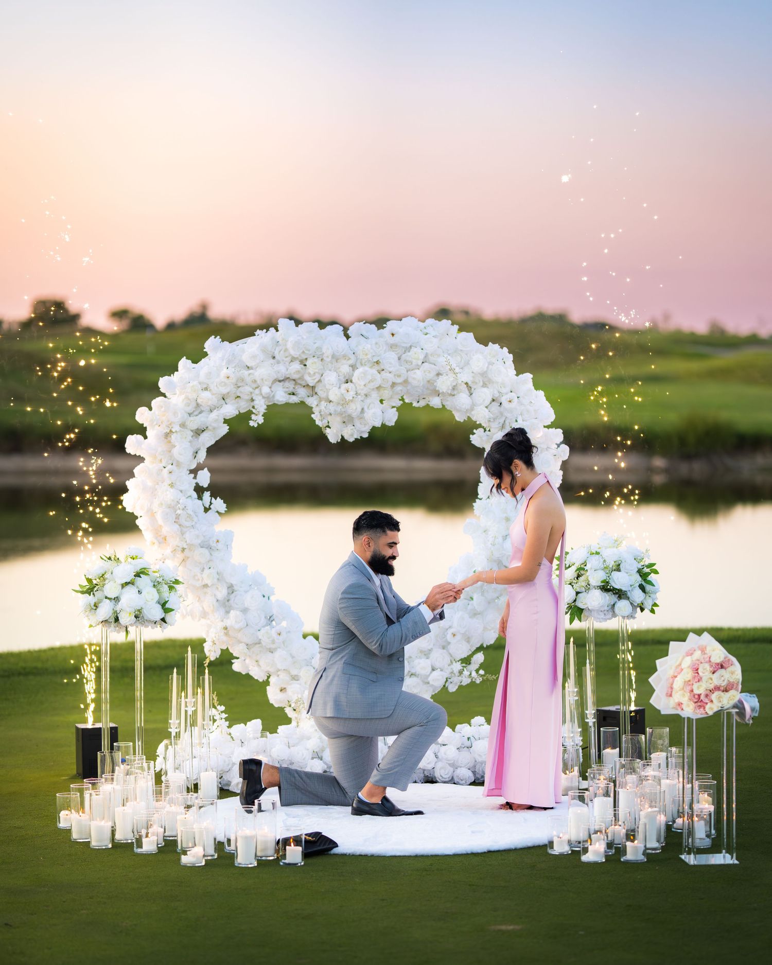 Couple sharing a special moment under an elegant white flower arch with glowing candles.