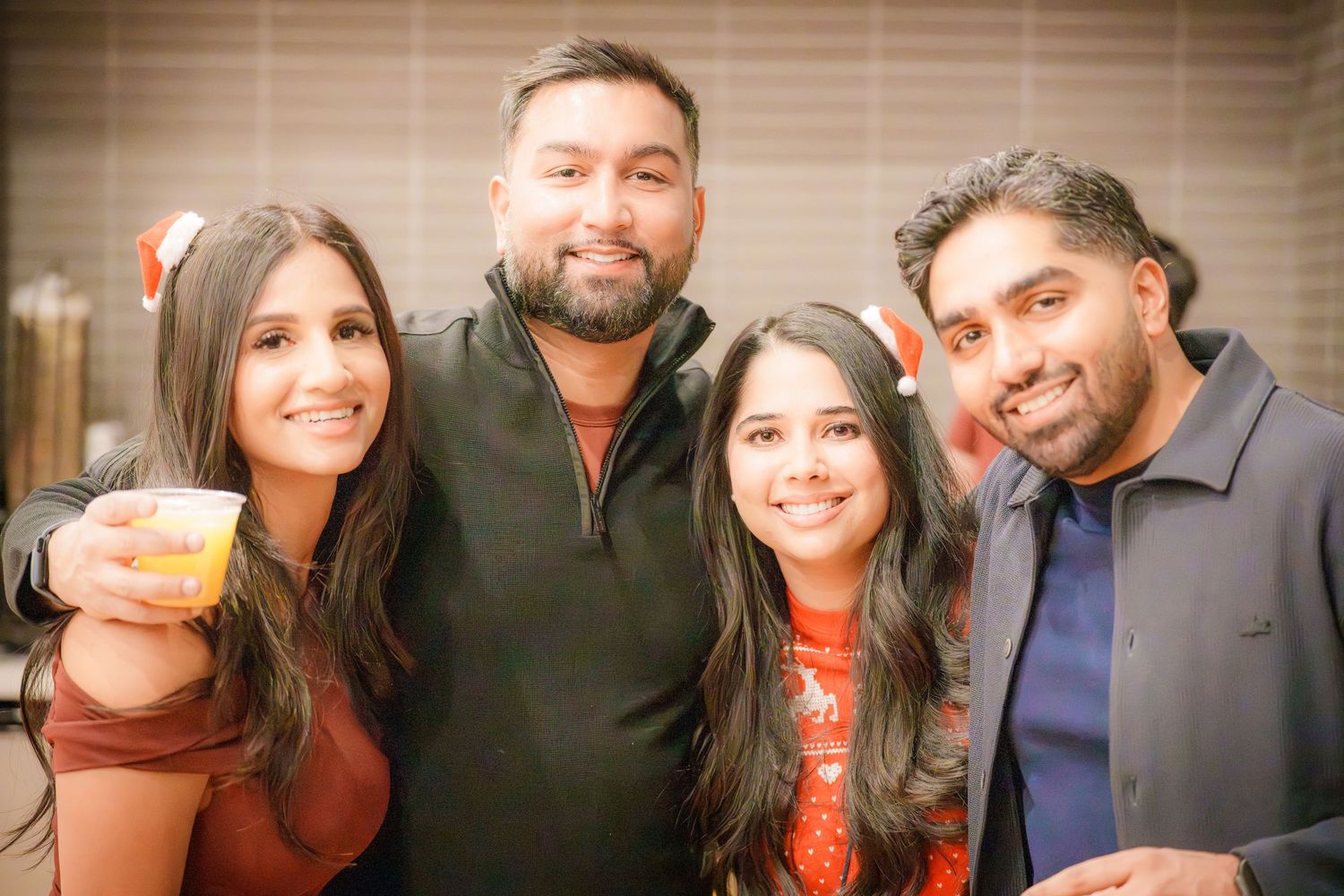 Friends posing together at a social gathering with warm lighting.