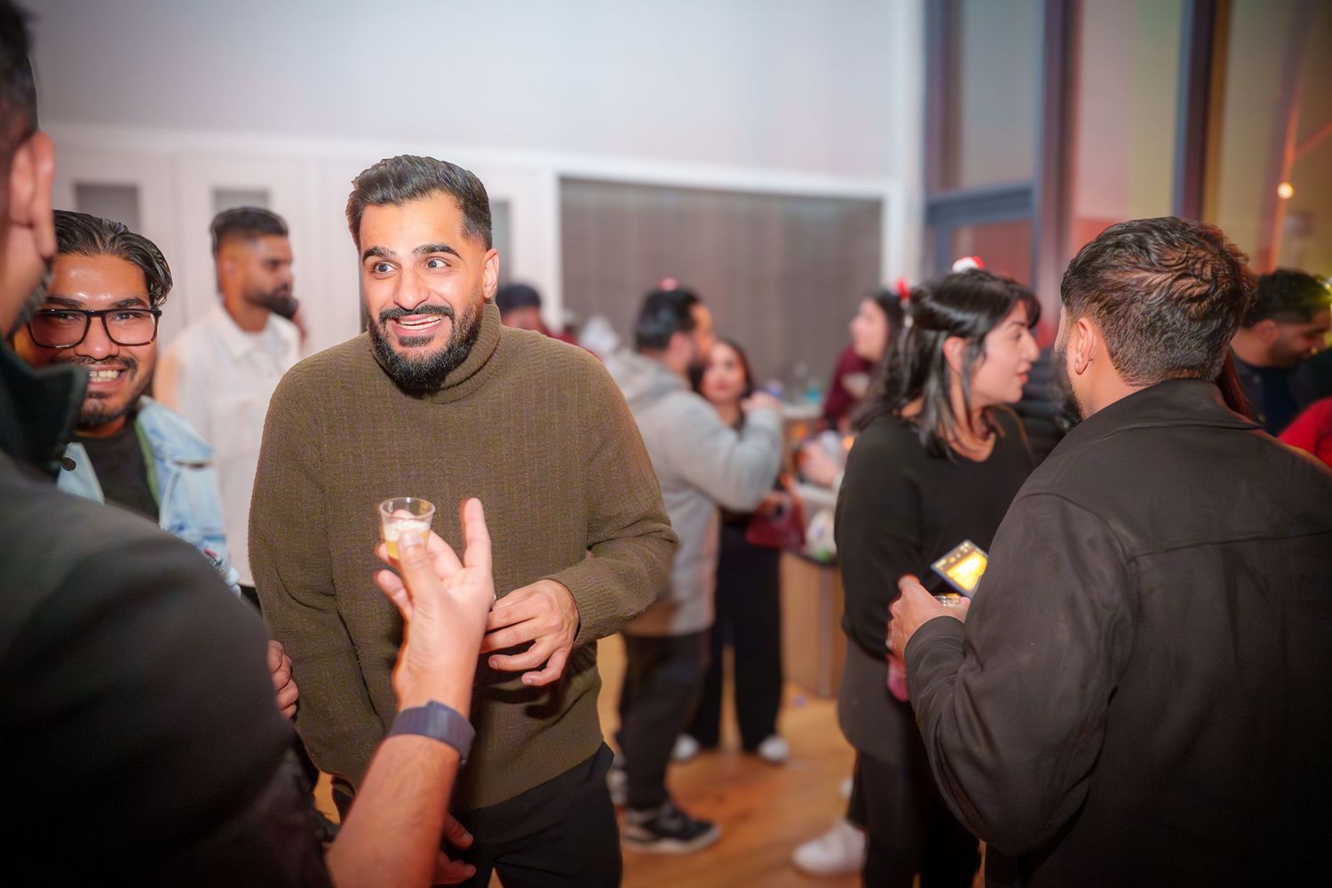 People mingling and socializing at an indoor party with warm lighting.