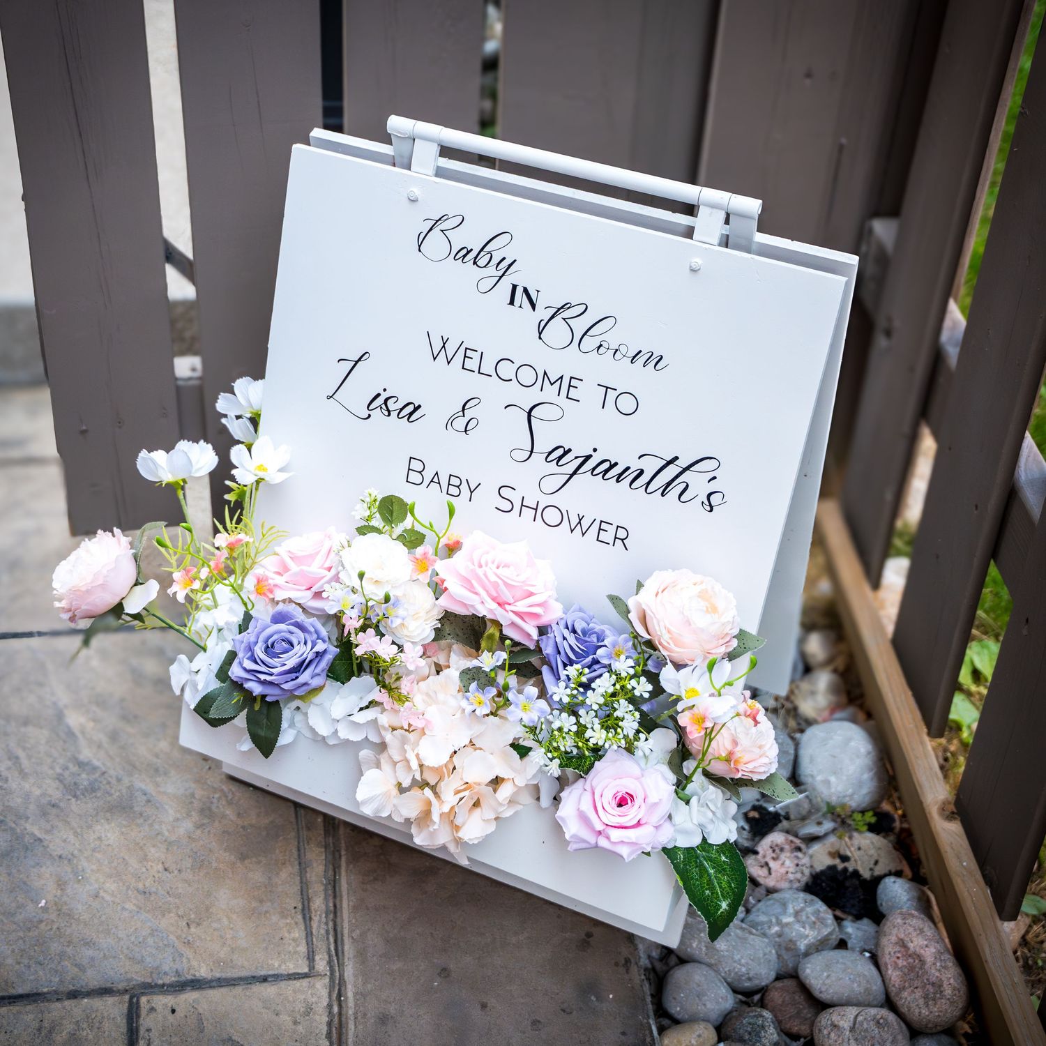 Decorative wedding welcome signs adorned with pink and purple floral arrangements.