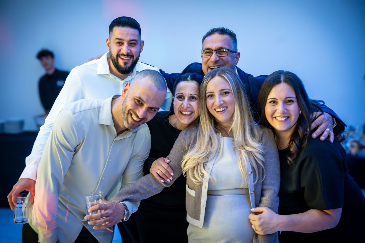 Group of friends posing together at a celebration with blue-tinted lighting effects.