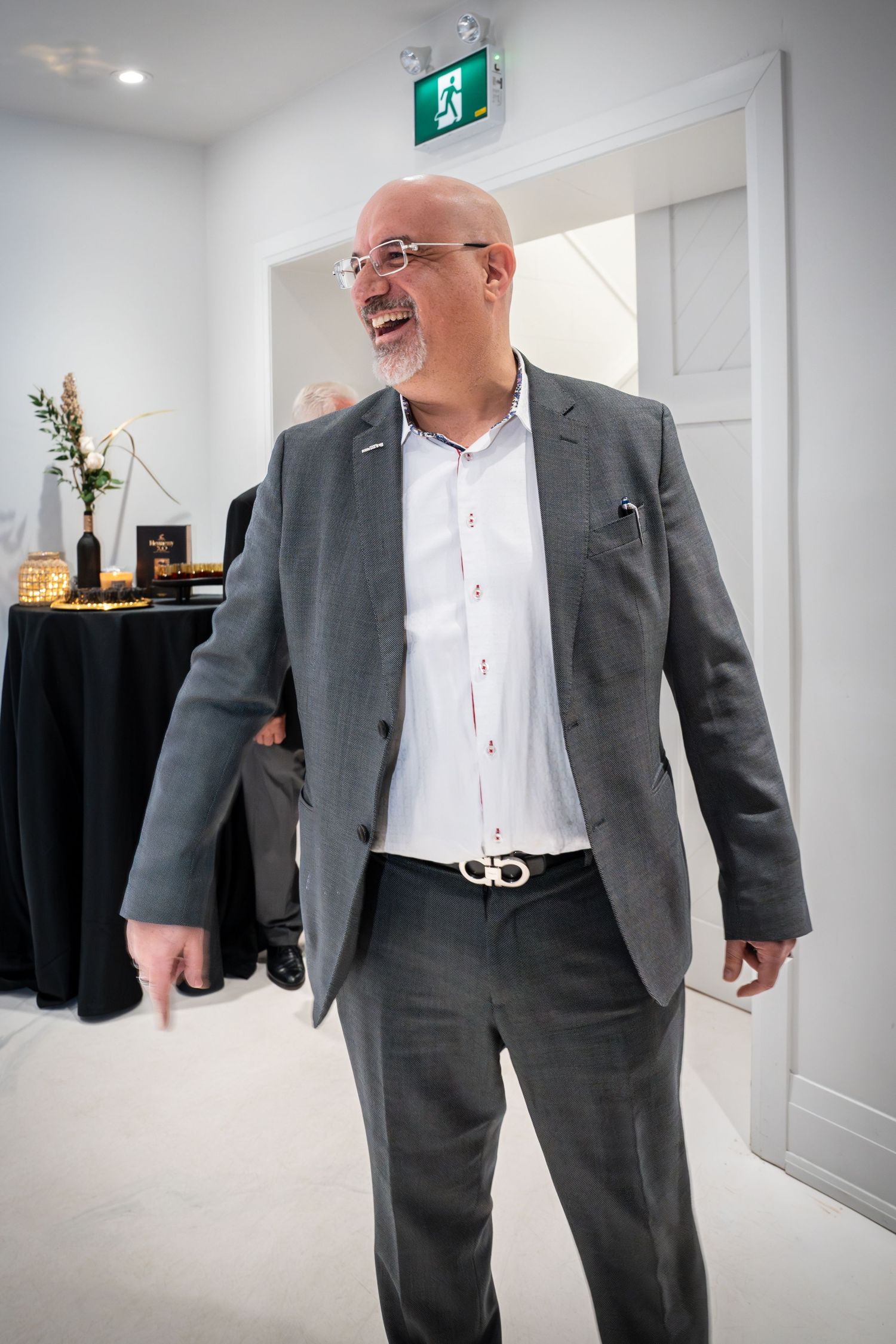 Business professionals walking through a modern white office space with an exit sign visible.