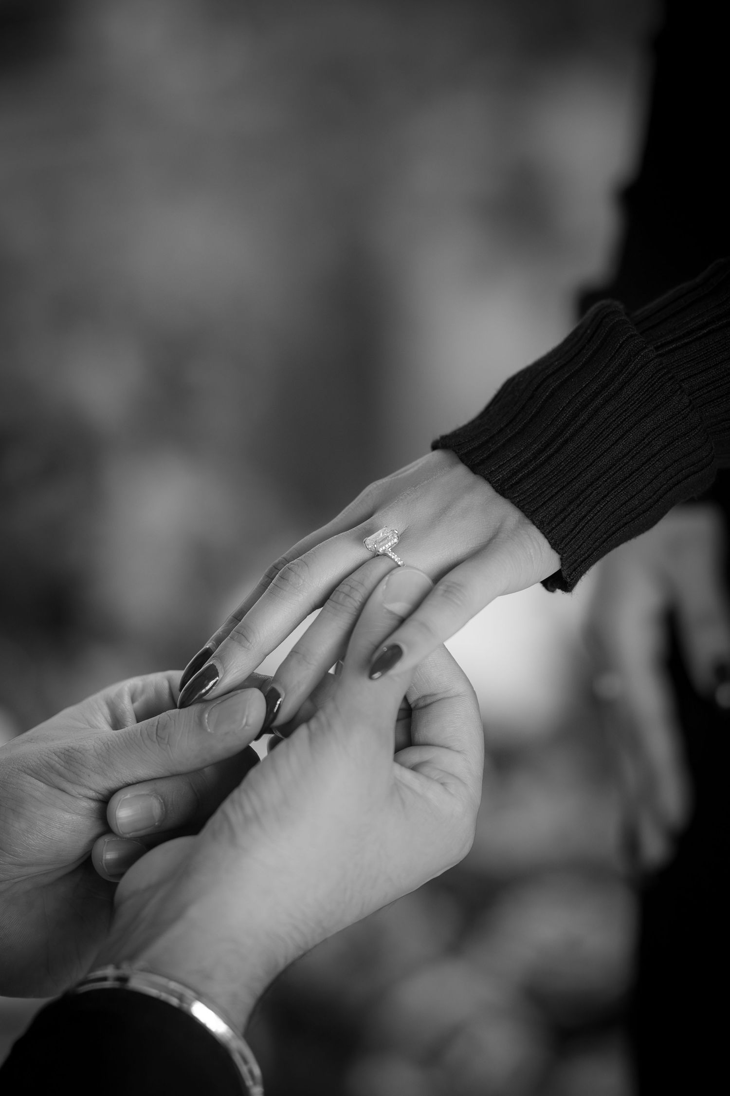 Intimate black and white shot of hands during proposal moment.