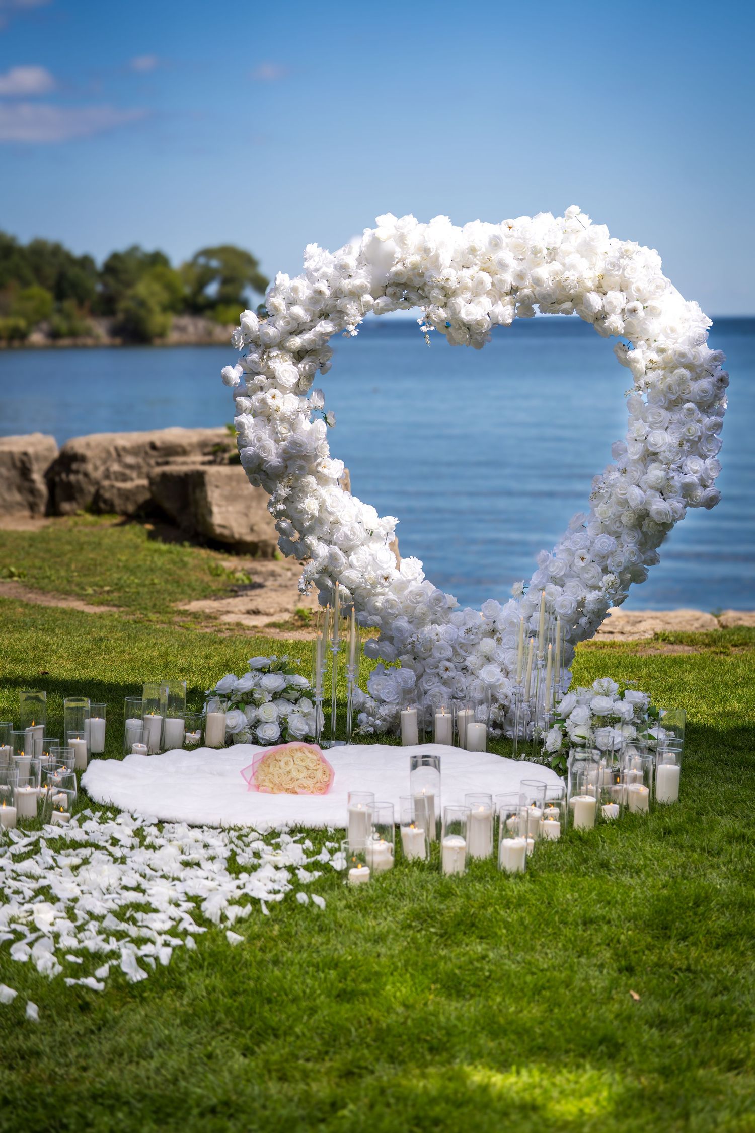 Elegant white balloon arch and candles set up for waterfront wedding ceremony.