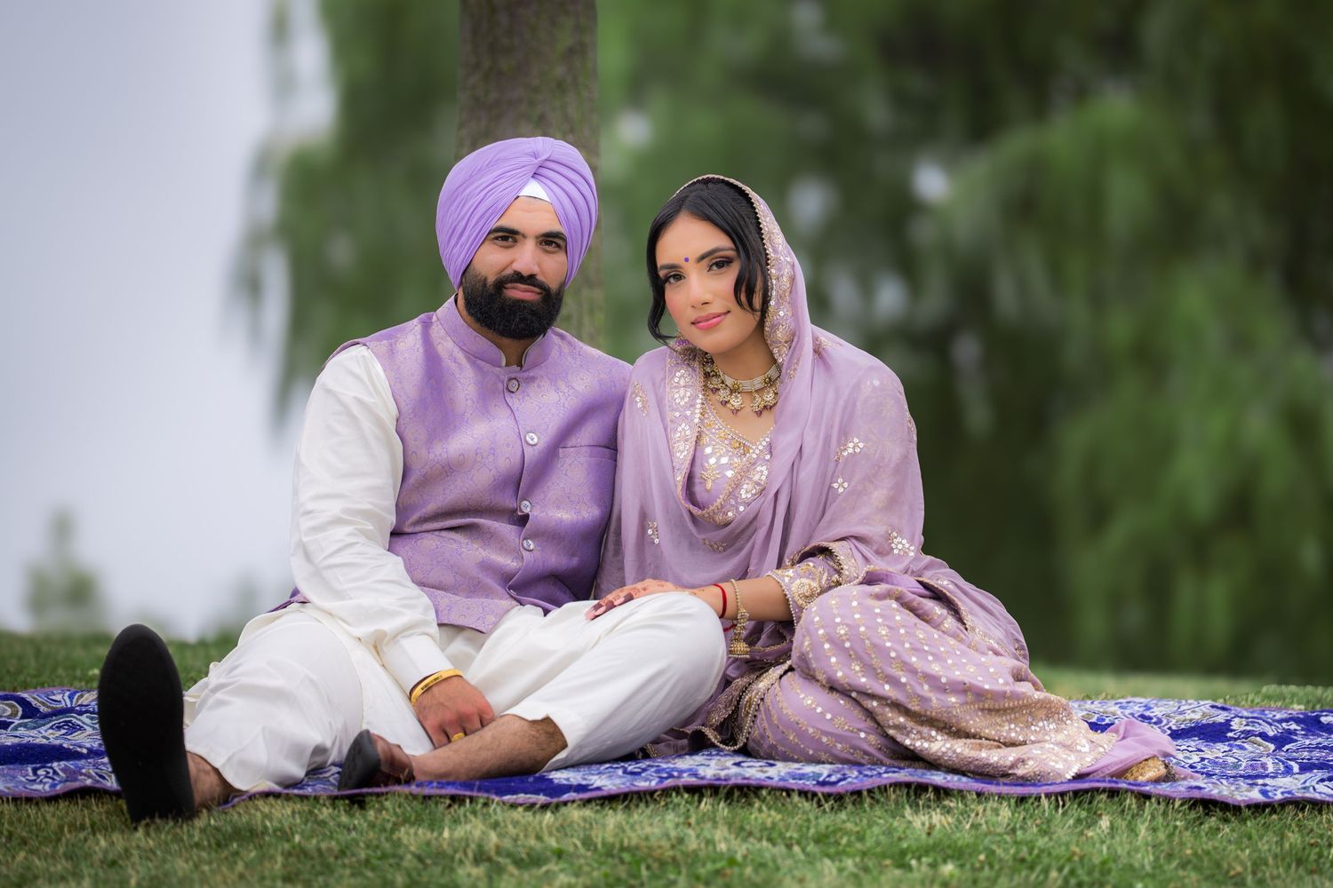 A couple in matching purple and white outfits poses together during their outdoor engagement session.