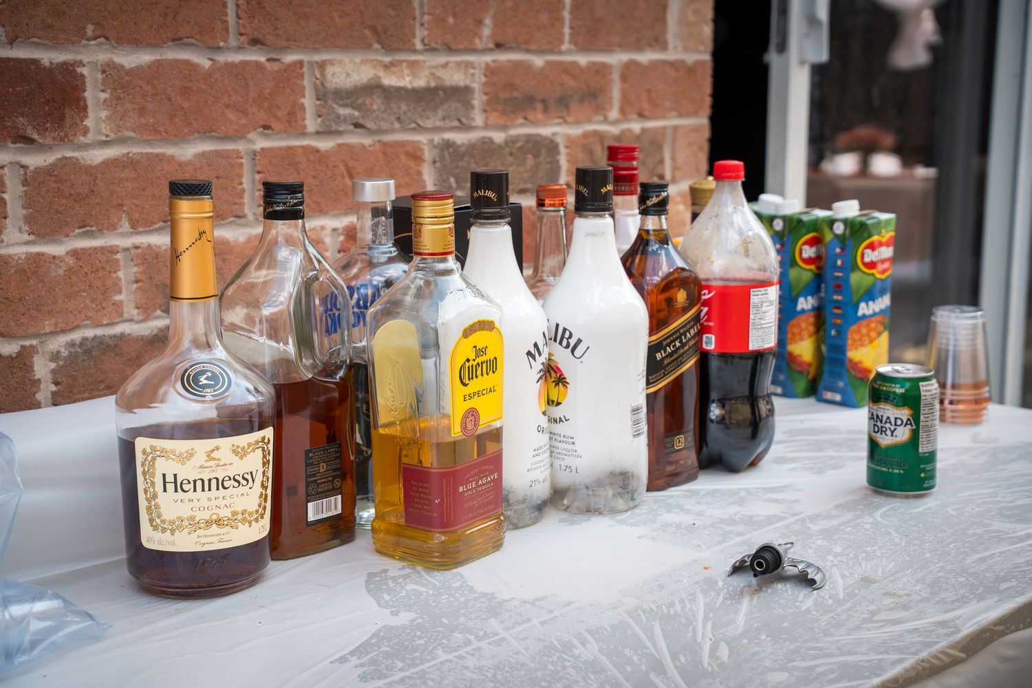 Assorted liquor bottles displayed on a rustic brick wall bar setup.