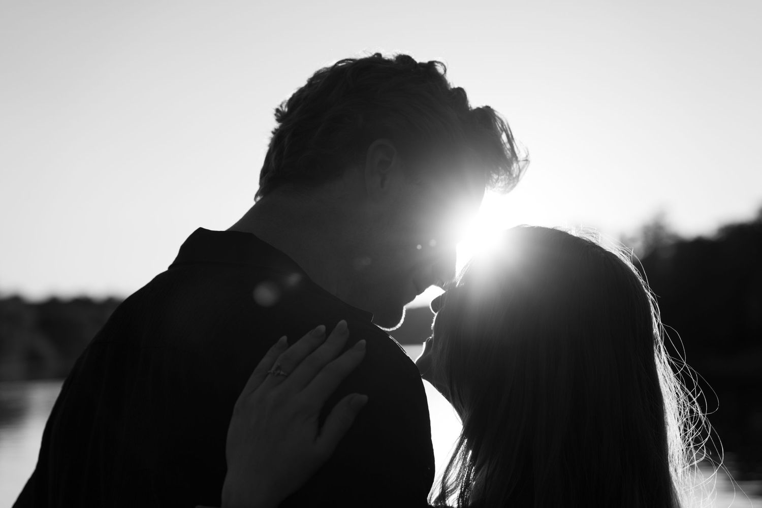 Romantic black and white silhouette of couple nearly kissing at sunset.