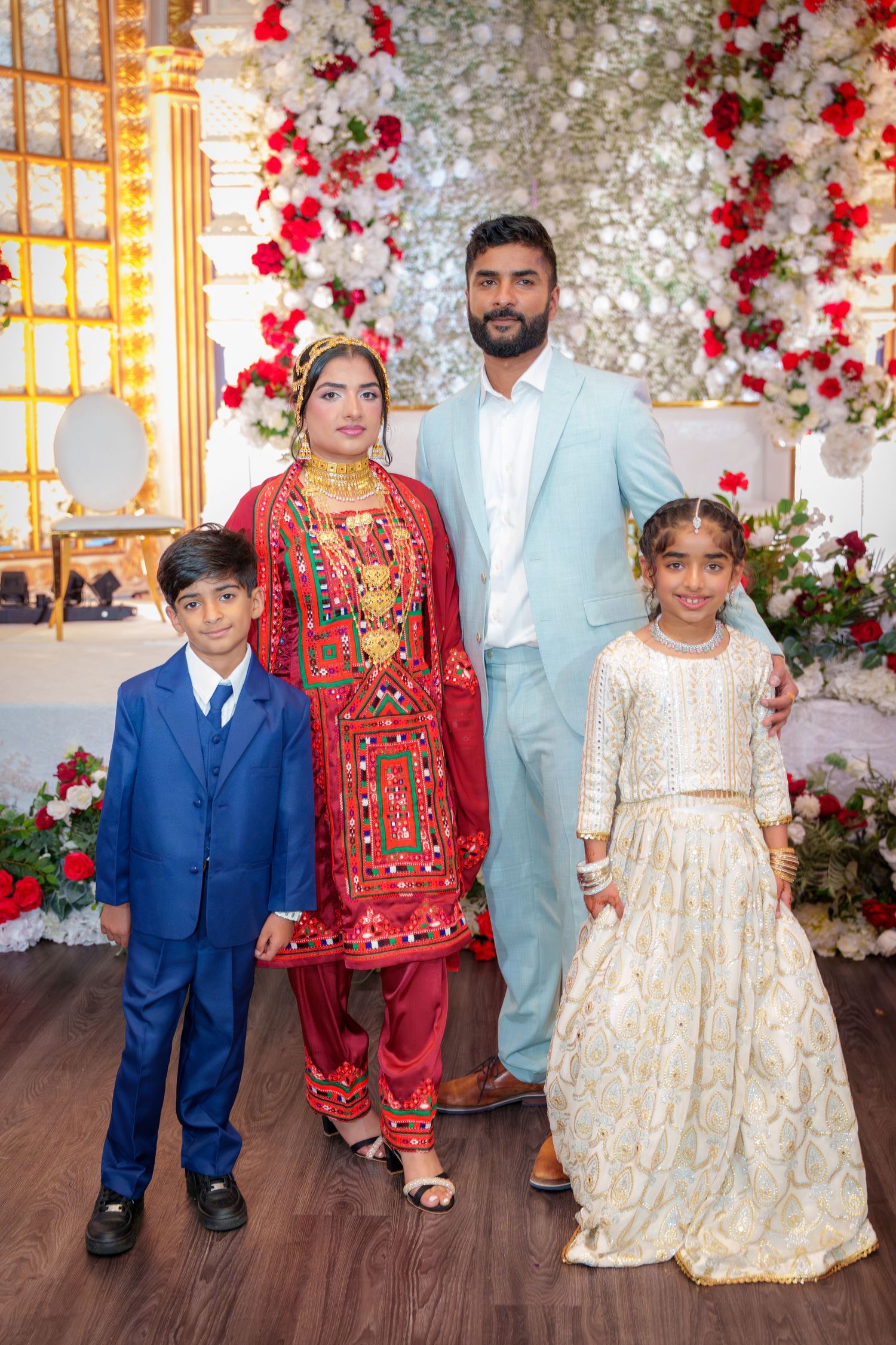 Family group photo with children in formal attire against floral backdrop.