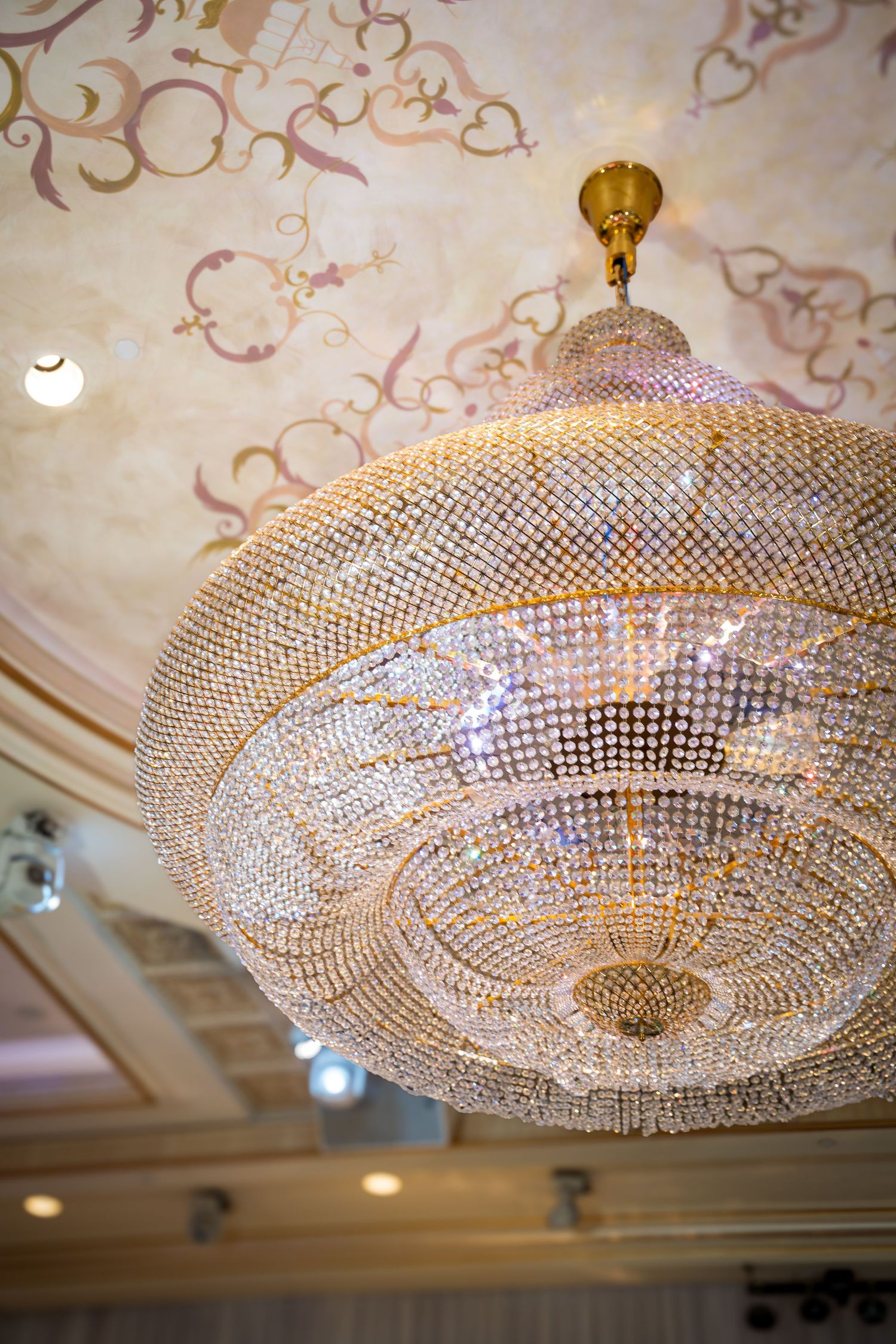 An elegant crystal chandelier with ornate ceiling details in a luxurious wedding venue.