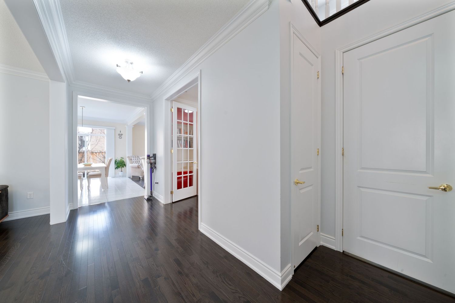 White hallway with crown molding features recessed lighting and multiple closed doors along the walls.