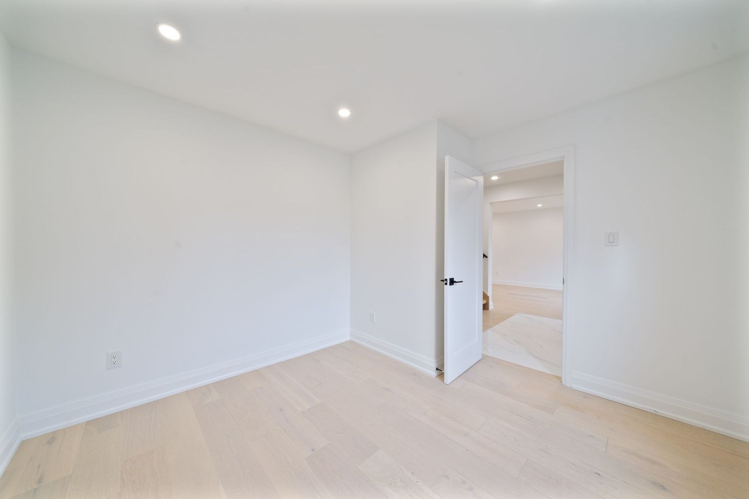 Modern white interior hallway with recessed lighting and multiple doorways visible in a residential space.