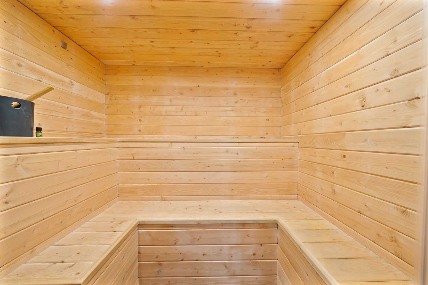 Interior view of a modern wooden sauna with pine walls and ceiling illuminated by recessed lighting.