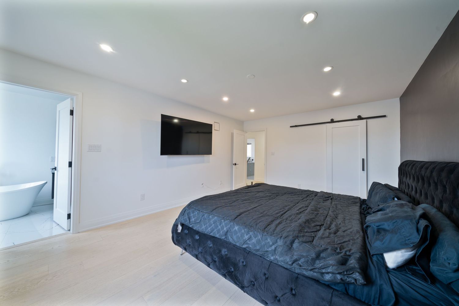Modern white bedroom interior with recessed lighting and navy blue bedding features clean minimalist design.