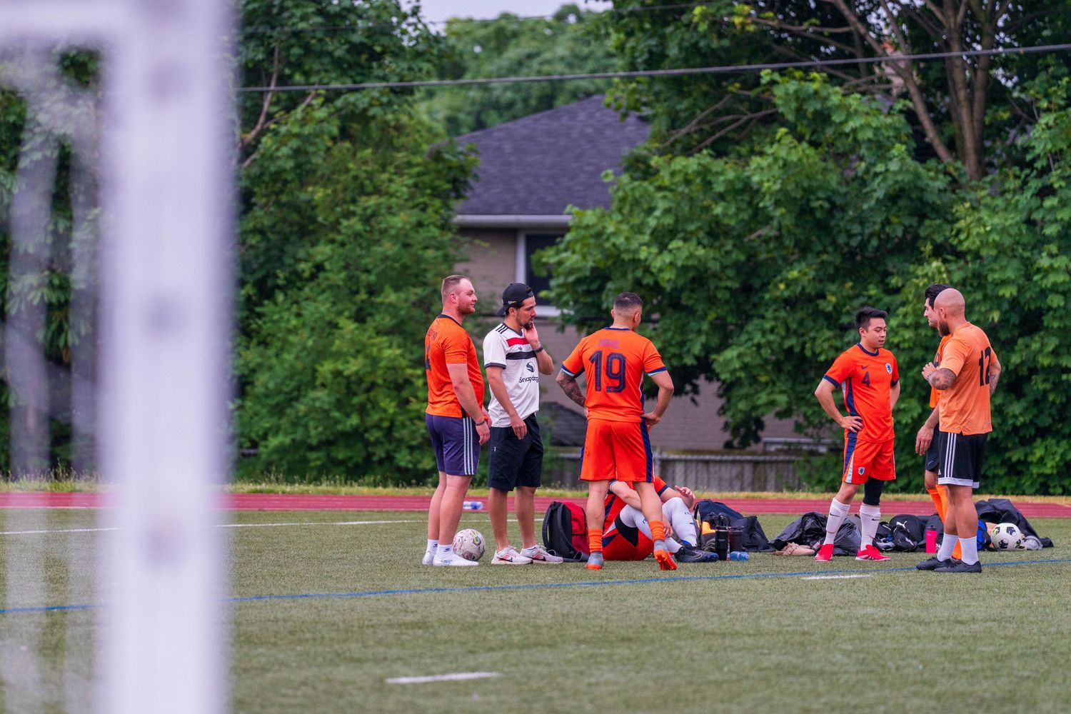 Players resting on sideline during soccer match break.