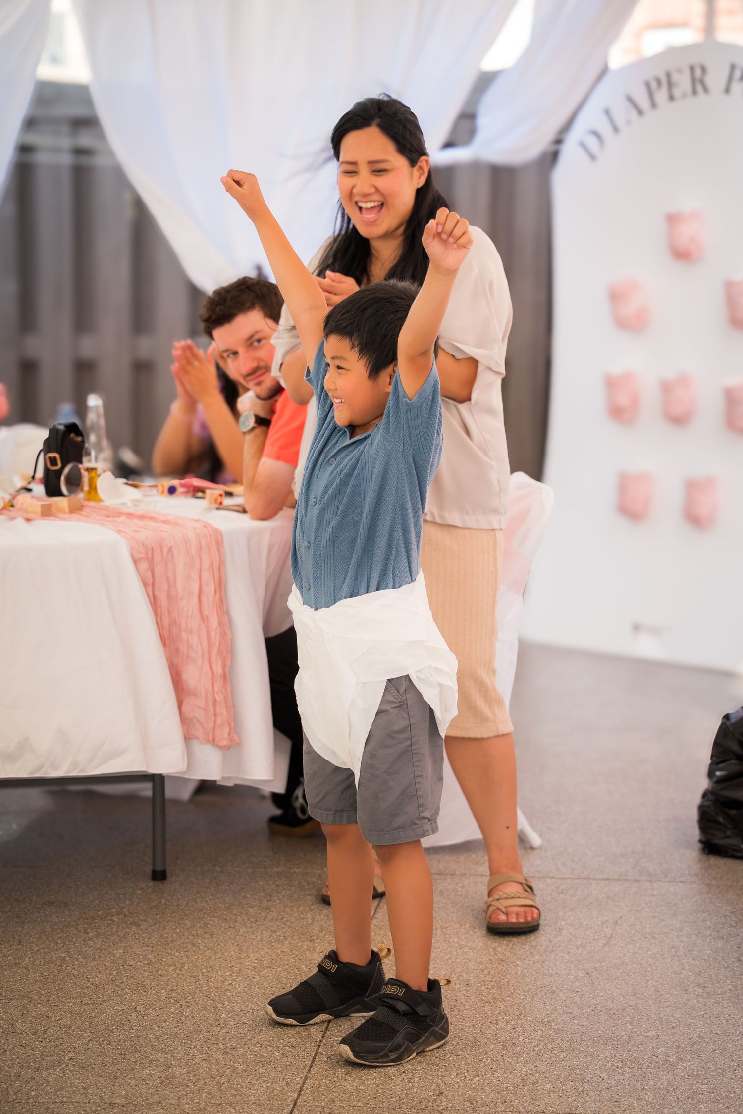 Family members dancing together at a party with white drapes and pink decorations.