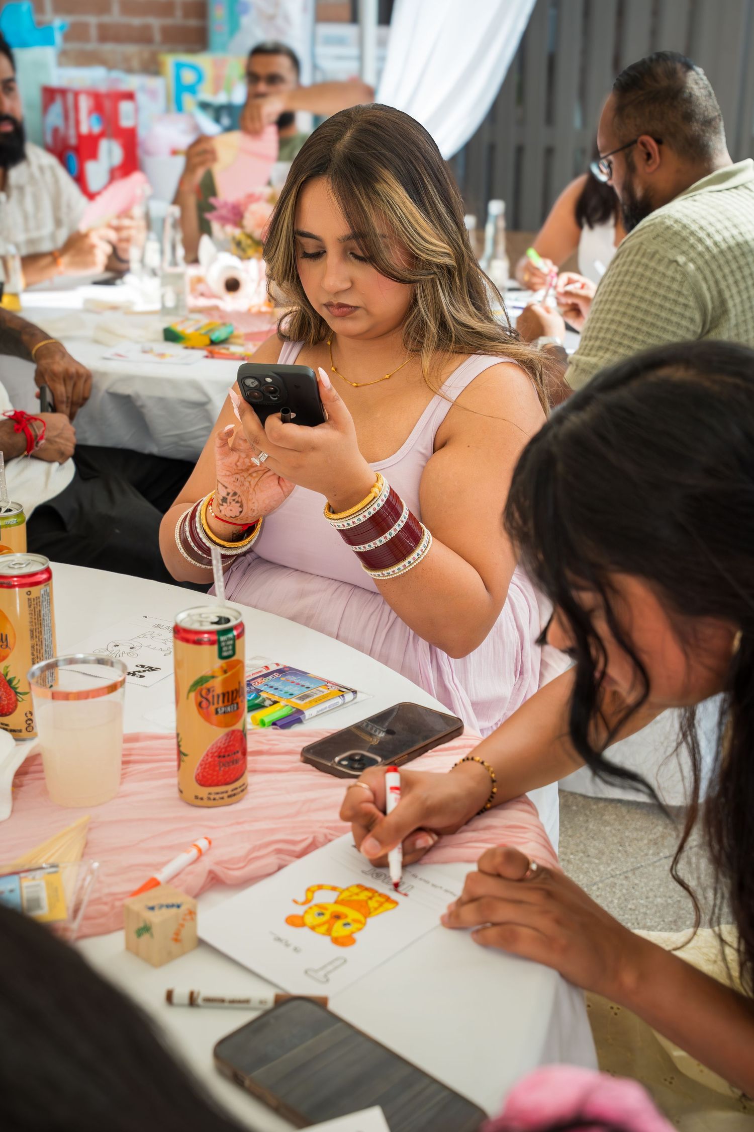 Group gathered at table with phones and drinks during social activity.