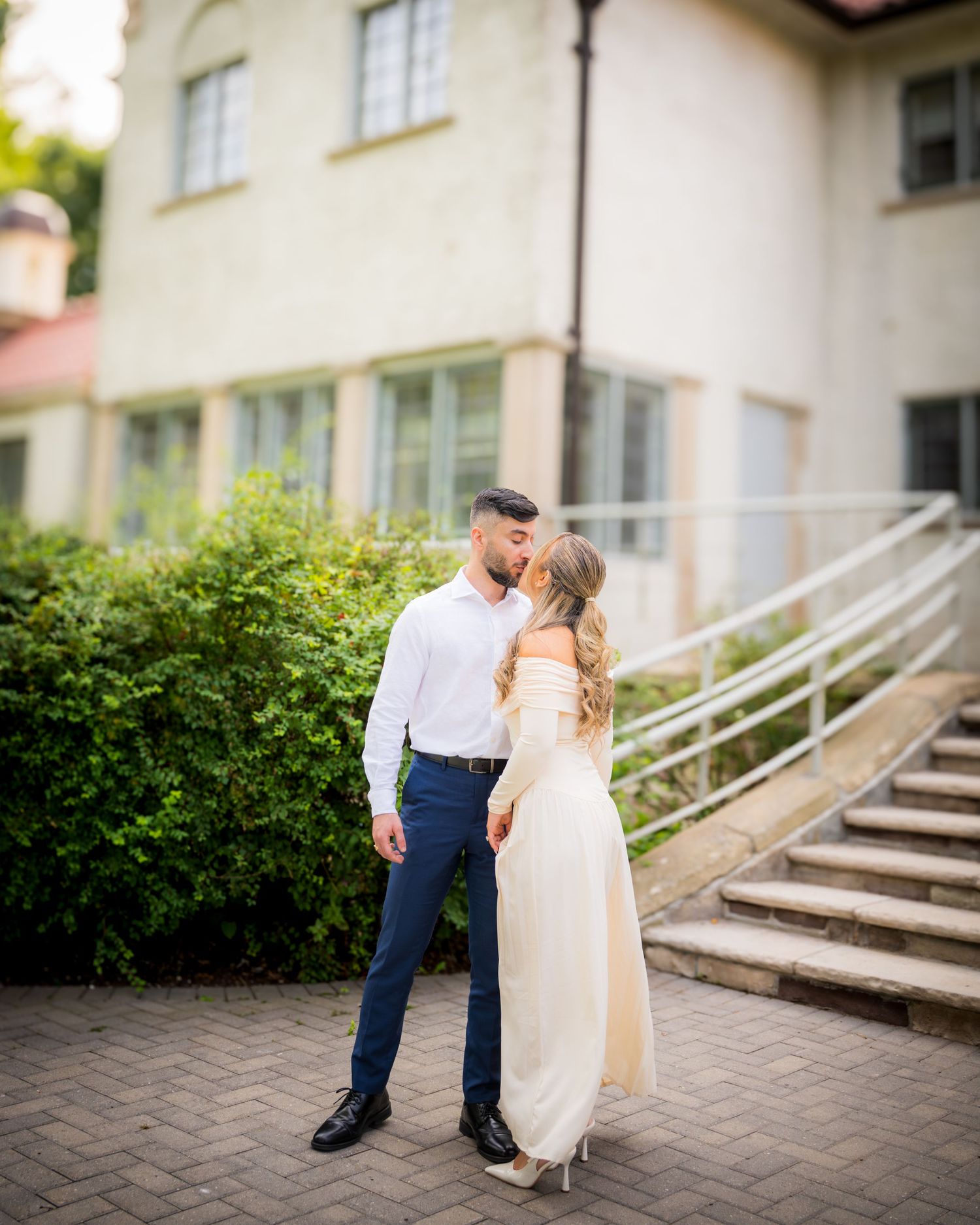 A couple poses on stone steps leading up to a building, creating a sweet moment together.
