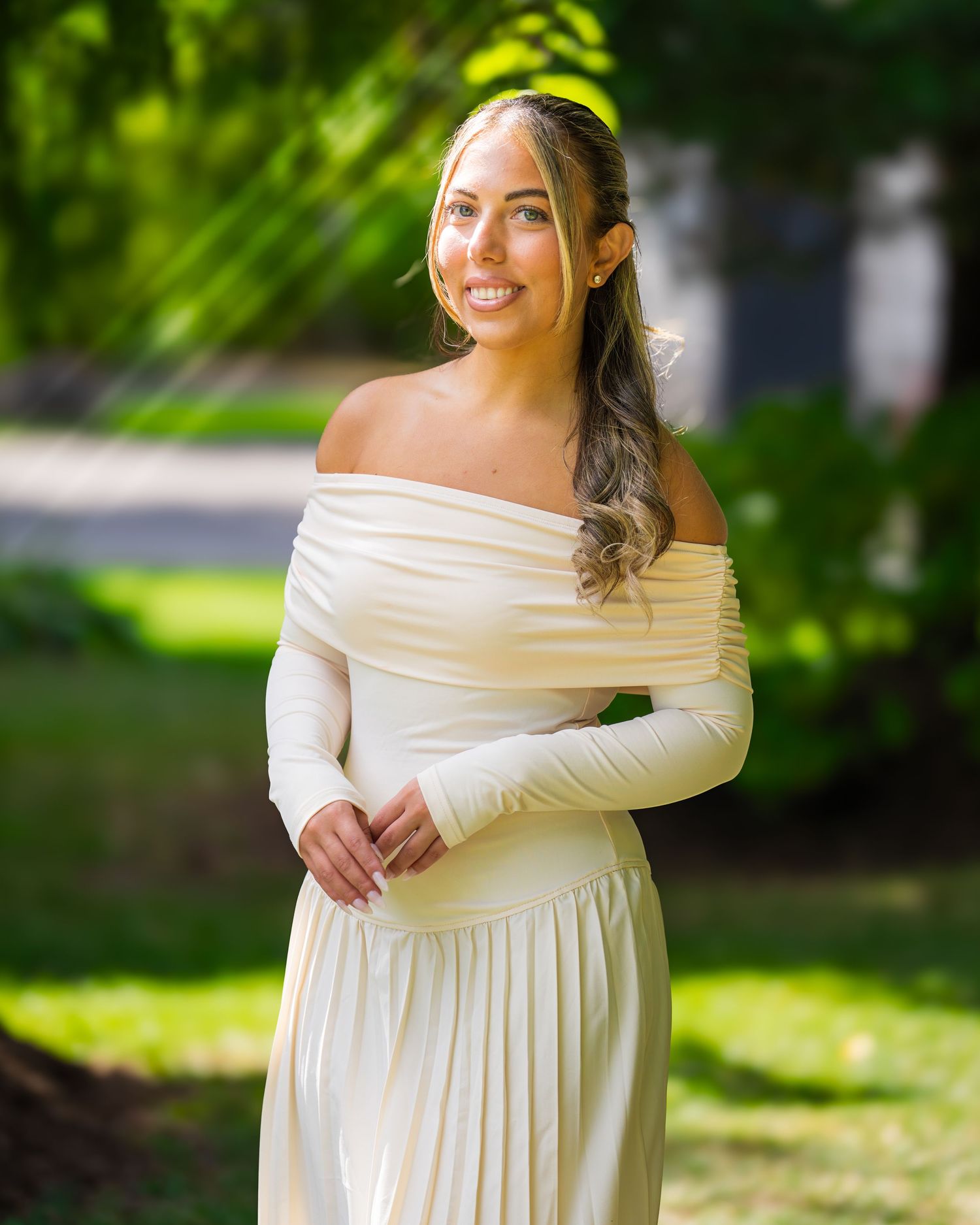 An elegant off-shoulder cream dress captured in an outdoor garden setting.
