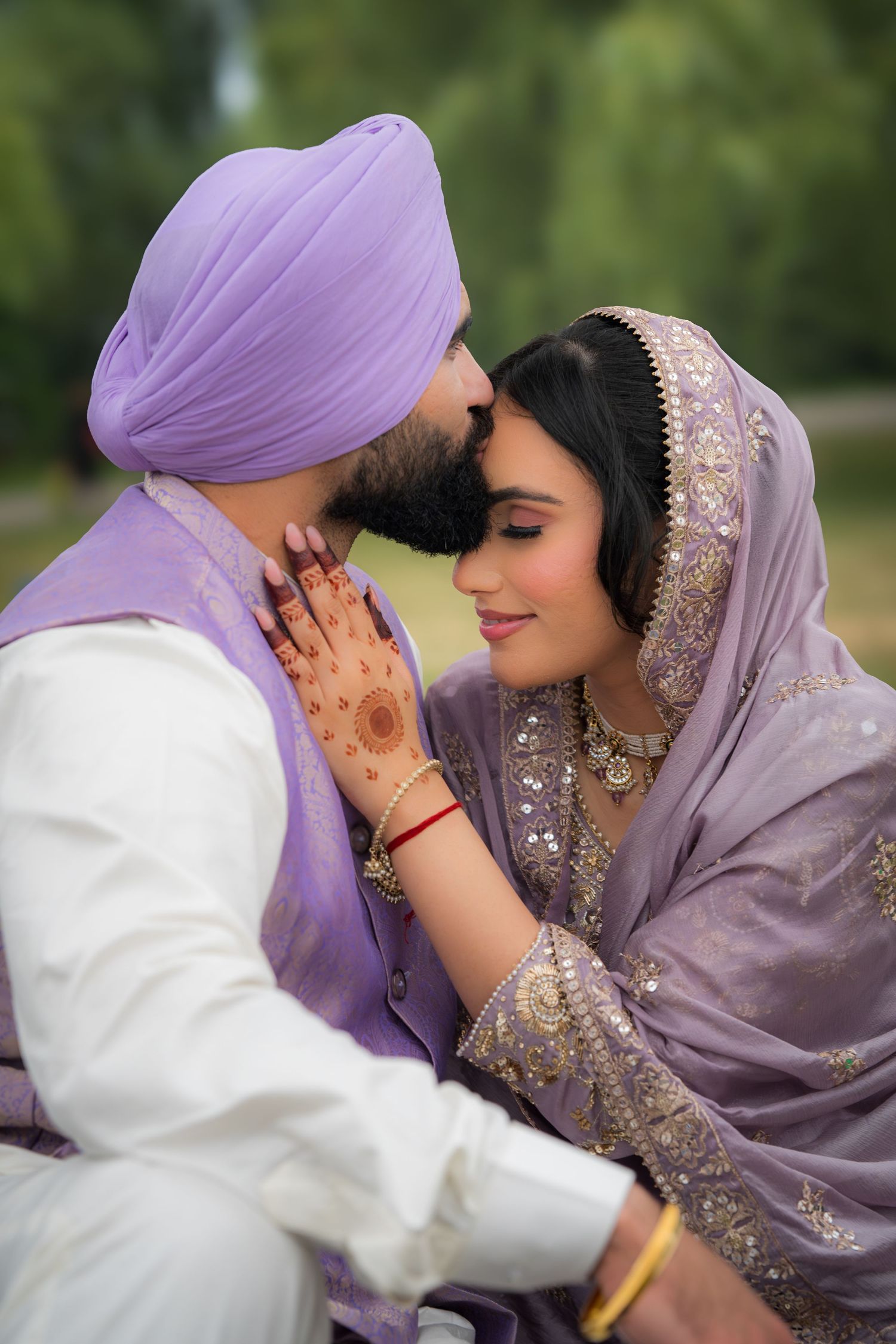 Intimate moment between newlyweds wearing coordinated purple and white traditional outfits.