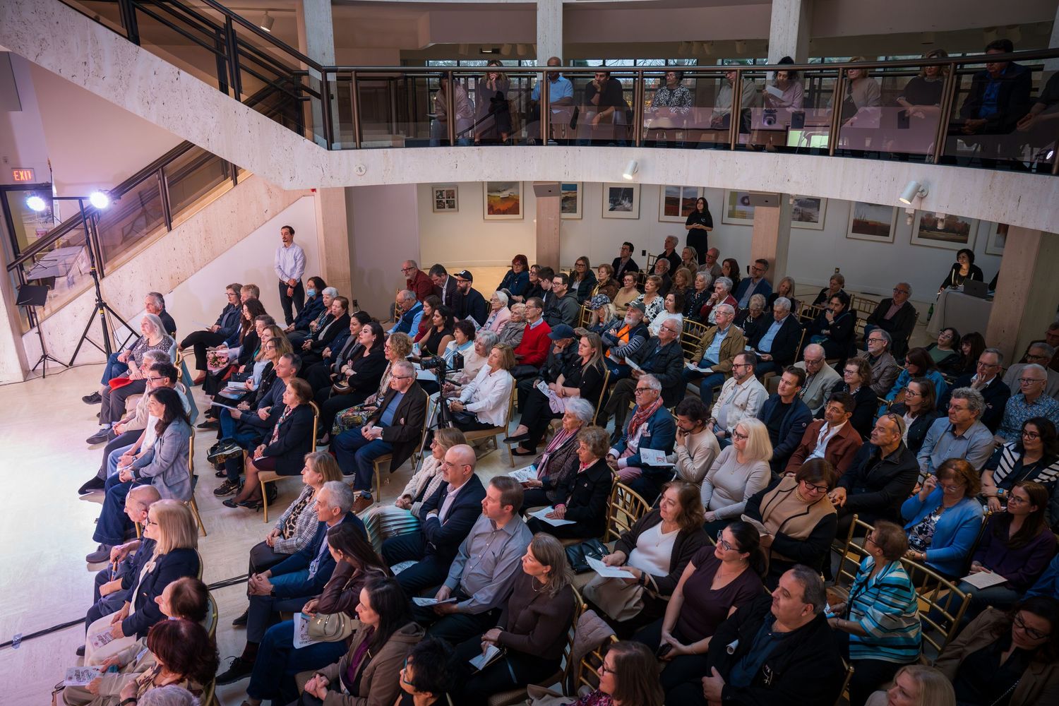 Large audience seated in a multi-level venue attending a formal event or conference.