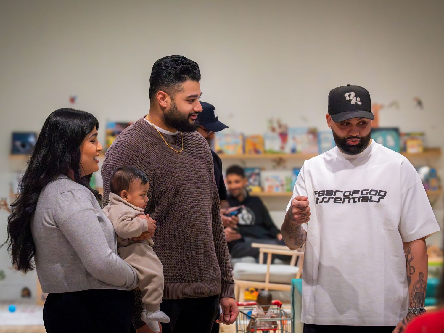 Three adults with a baby socializing at an indoor birthday party event.
