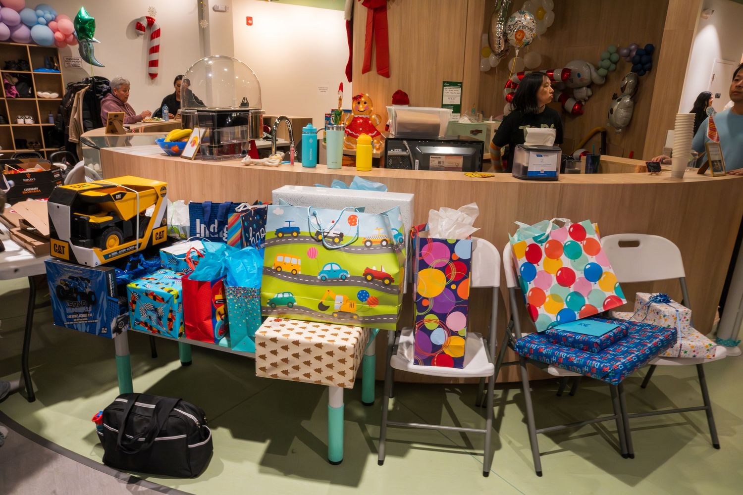 Colorful wrapped birthday gifts and presents displayed on chairs and a table inside a festive party venue.