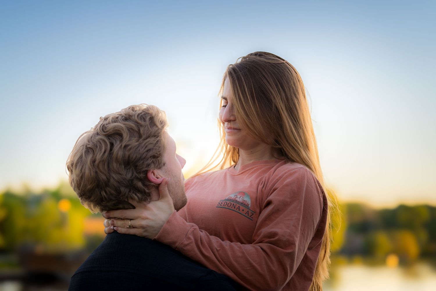 Young couple sharing a romantic moment at sunset, woman smiling with eyes closed holding mans face.