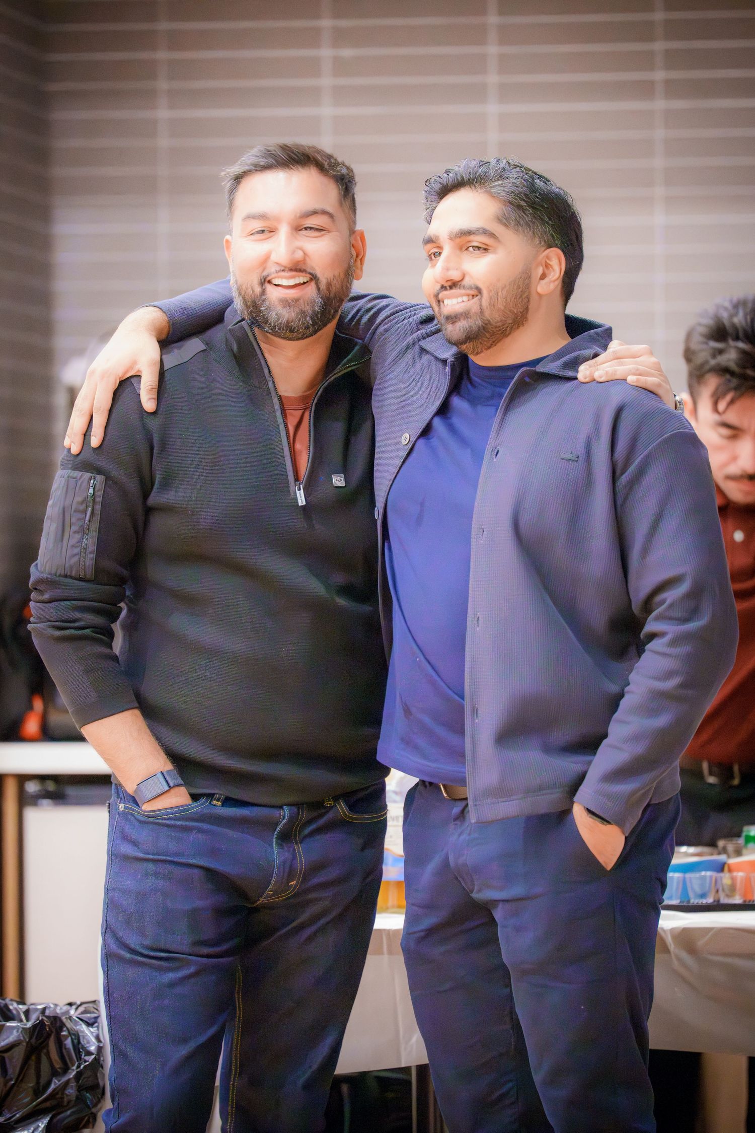 Two people in navy blue outfits share a friendly moment at an indoor event.