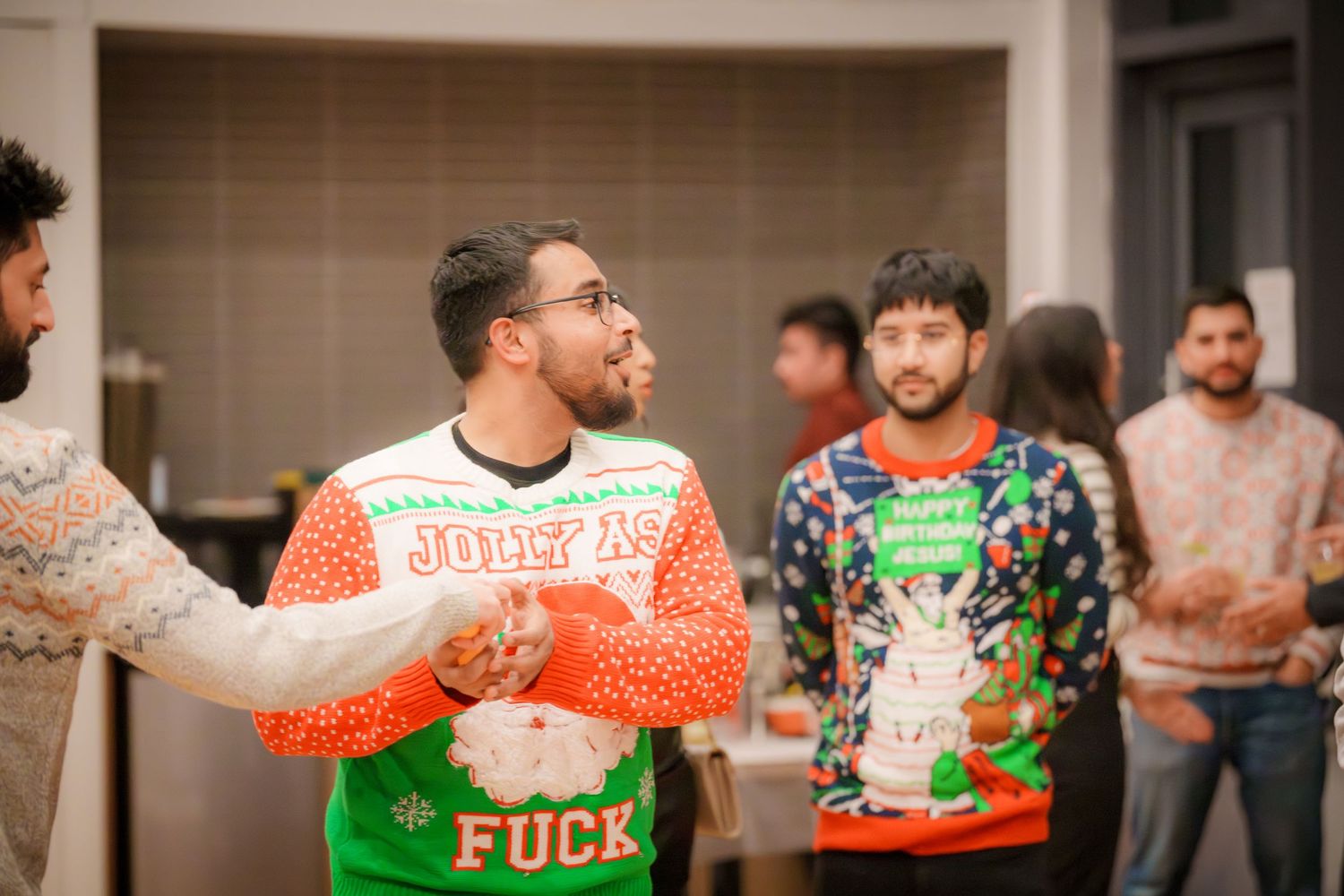 Friends in ugly Christmas sweaters share a laugh at a holiday gathering.