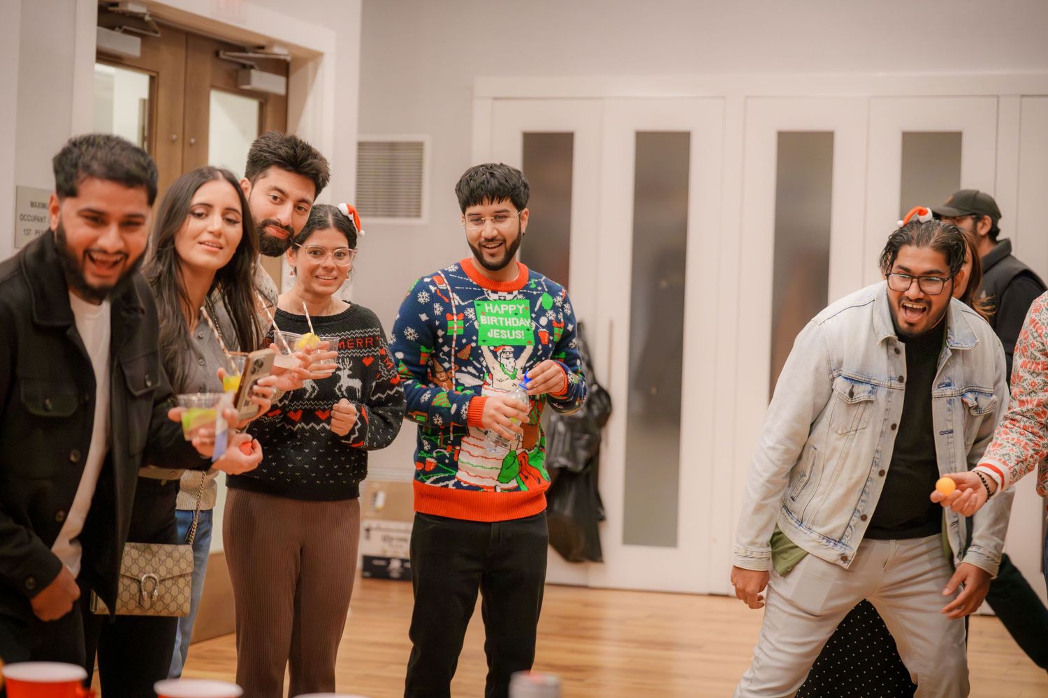 People socializing at an indoor holiday party with festive decorations.