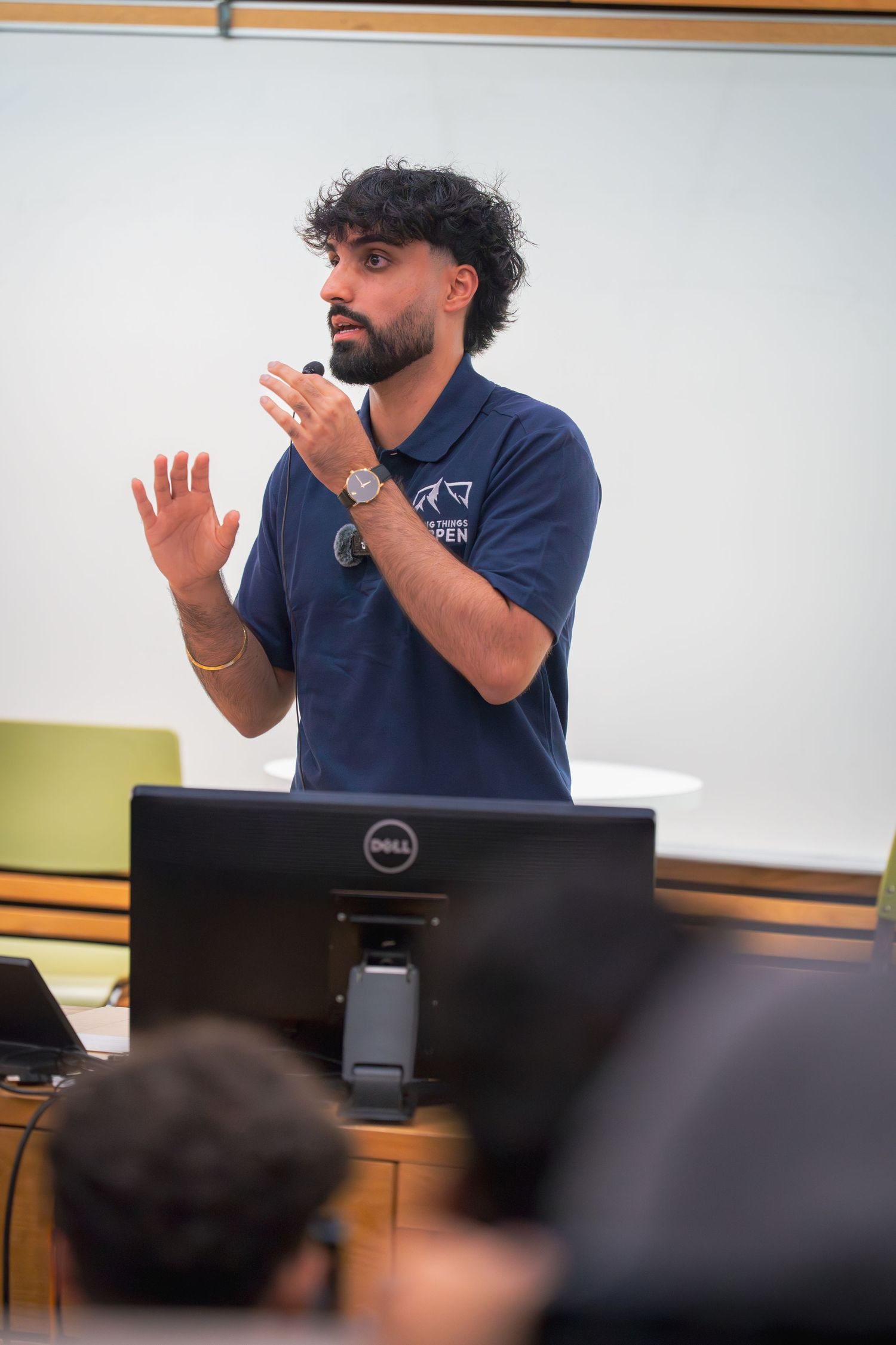 Speaker giving animated presentation while standing behind laptop in lecture hall.
