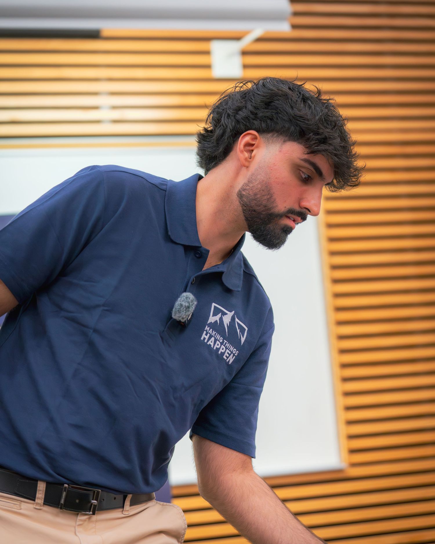 Presenter wearing navy polo shirt with company logo during conference presentation.