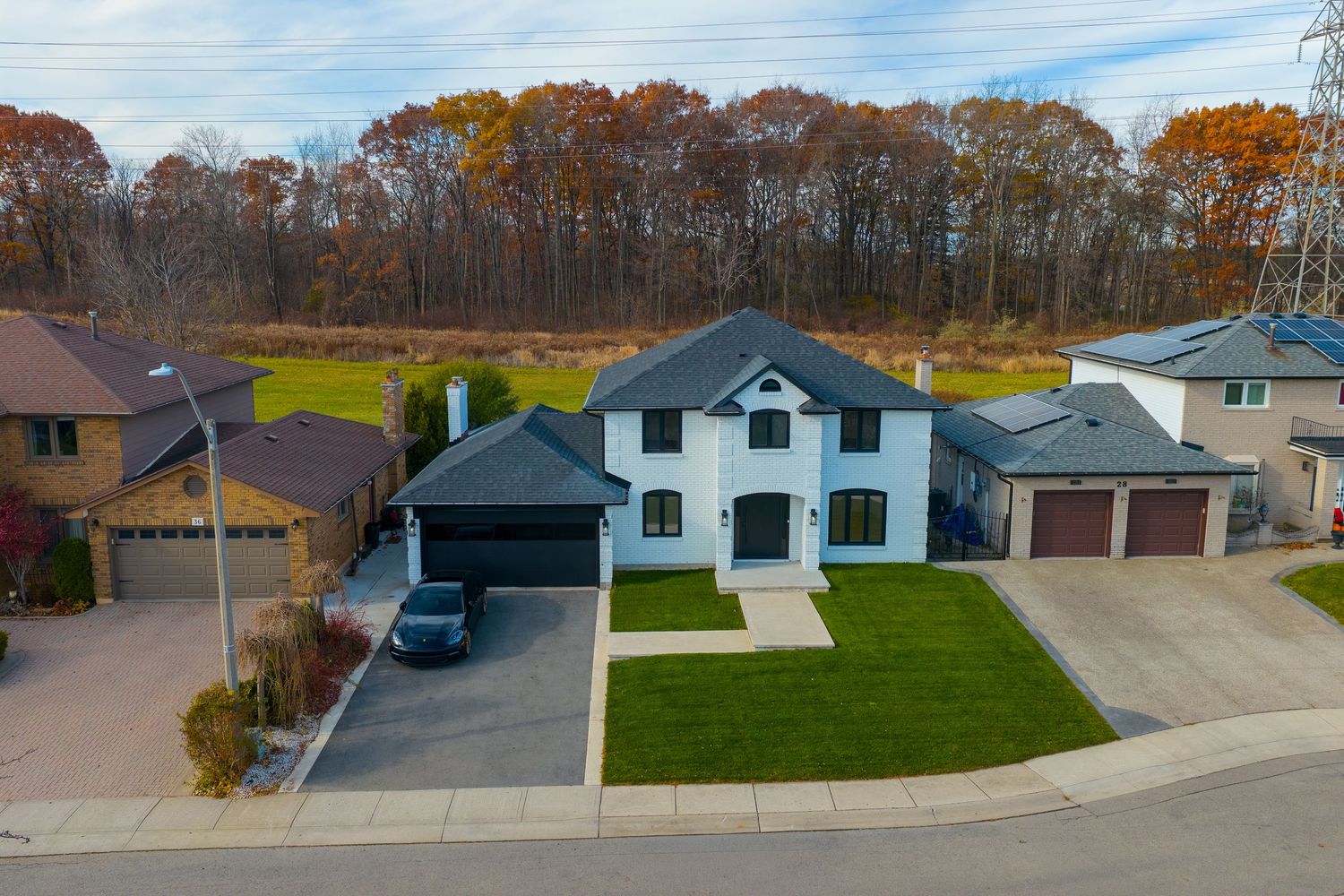 Aerial drone view of residential homes and streets in a suburban neighborhood during autumn with fall foliage.
