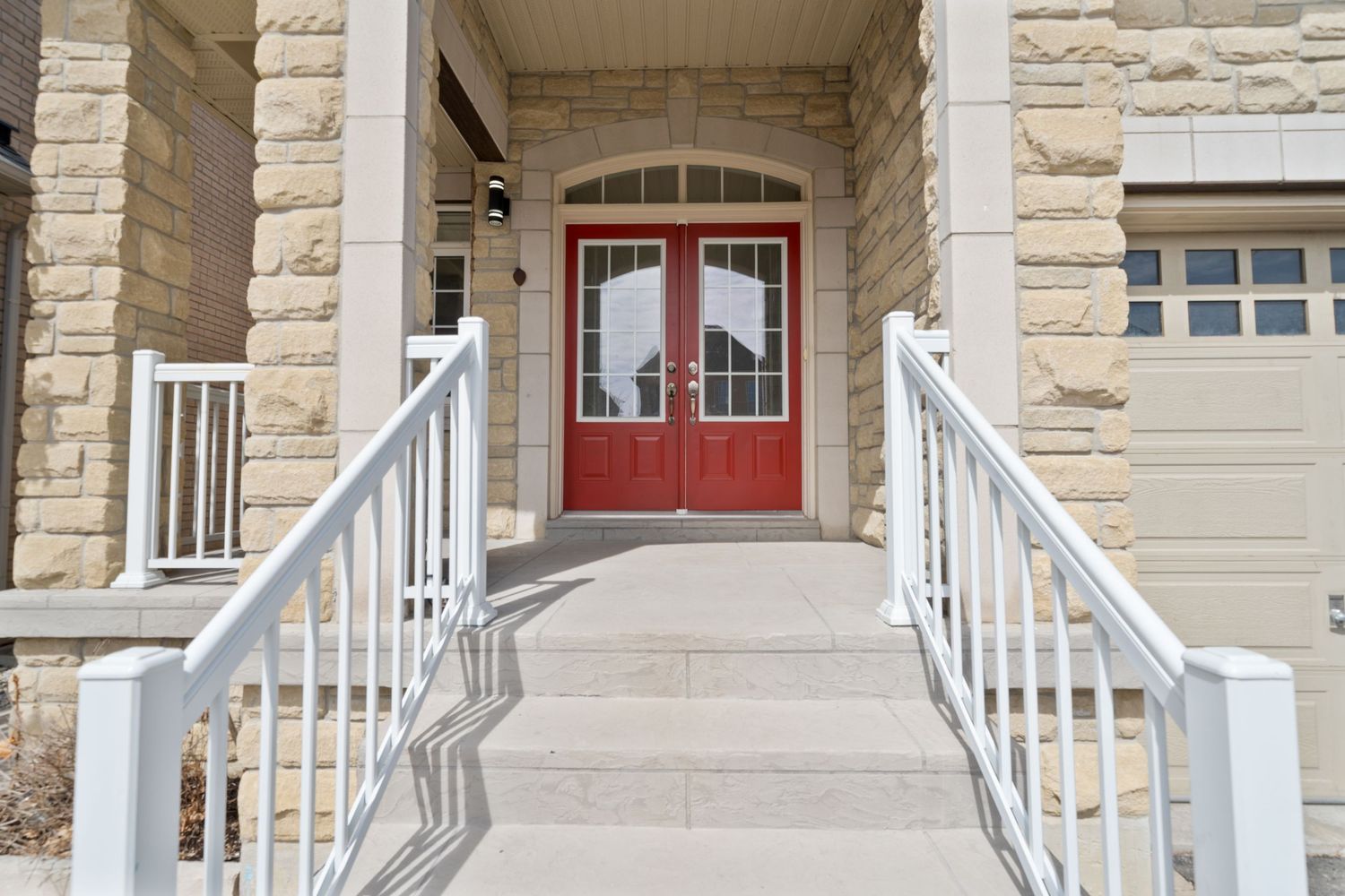 A row of white porch railings and columns along a stone building facade with red accents.
