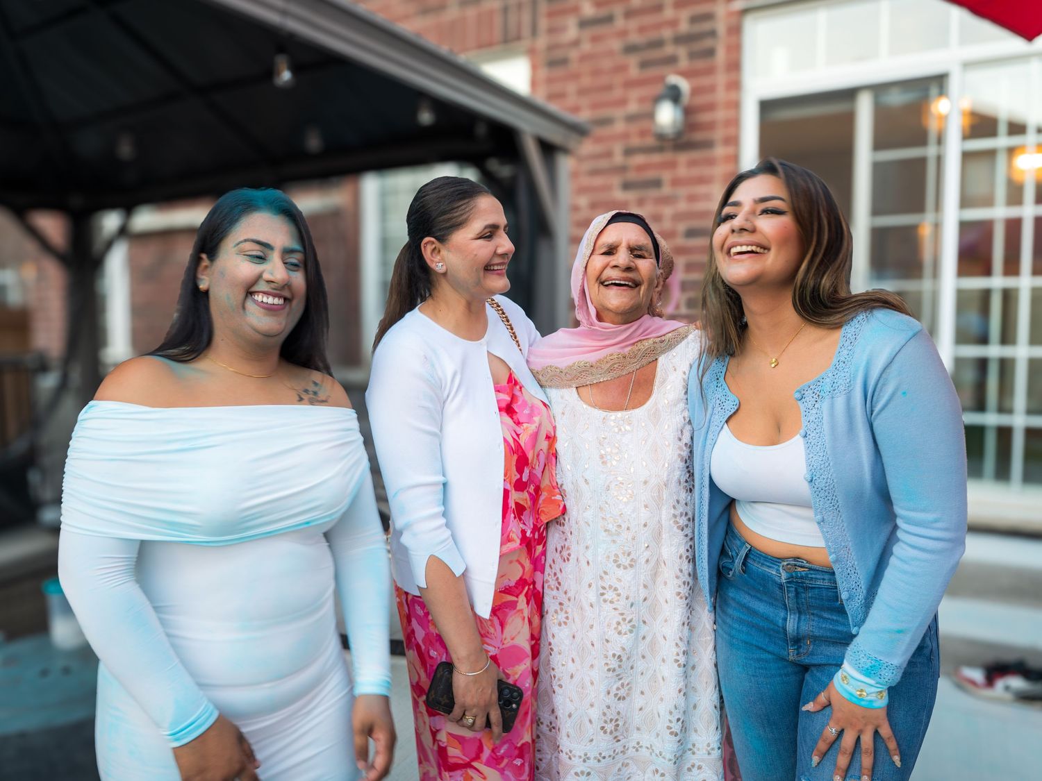 Four women smiling together at an outdoor gender reveal celebration in a backyard.