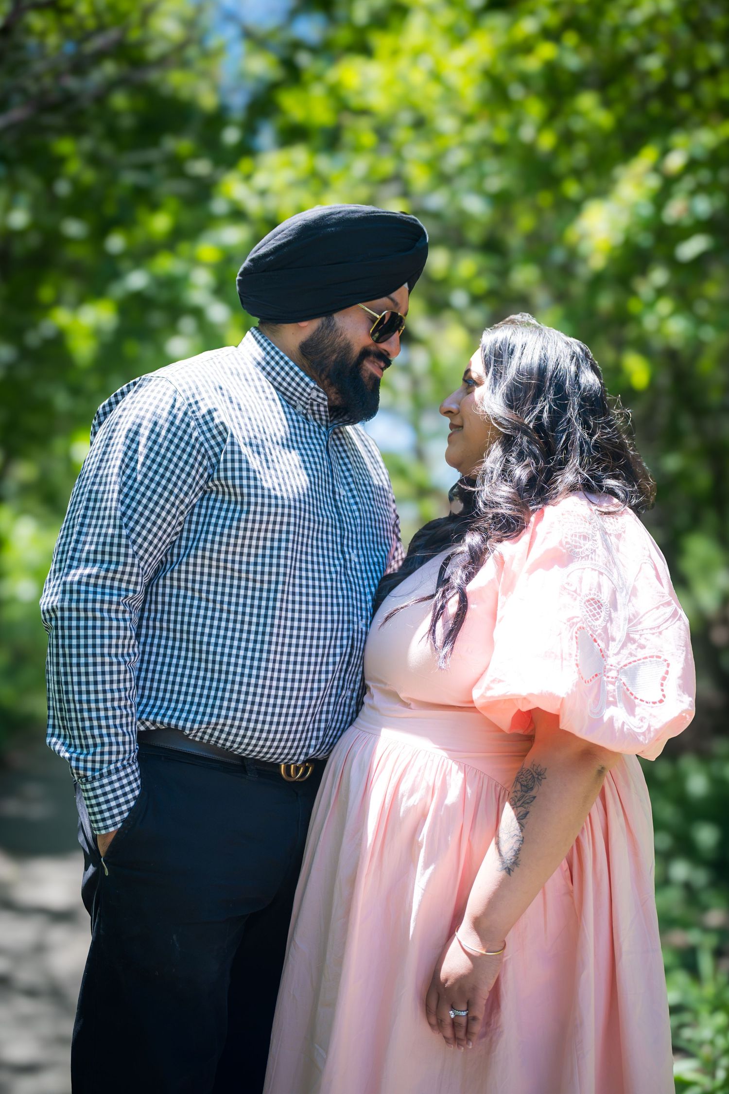 Couple in outdoor park, man in turban and plaid shirt, woman in pink puff sleeve dress.