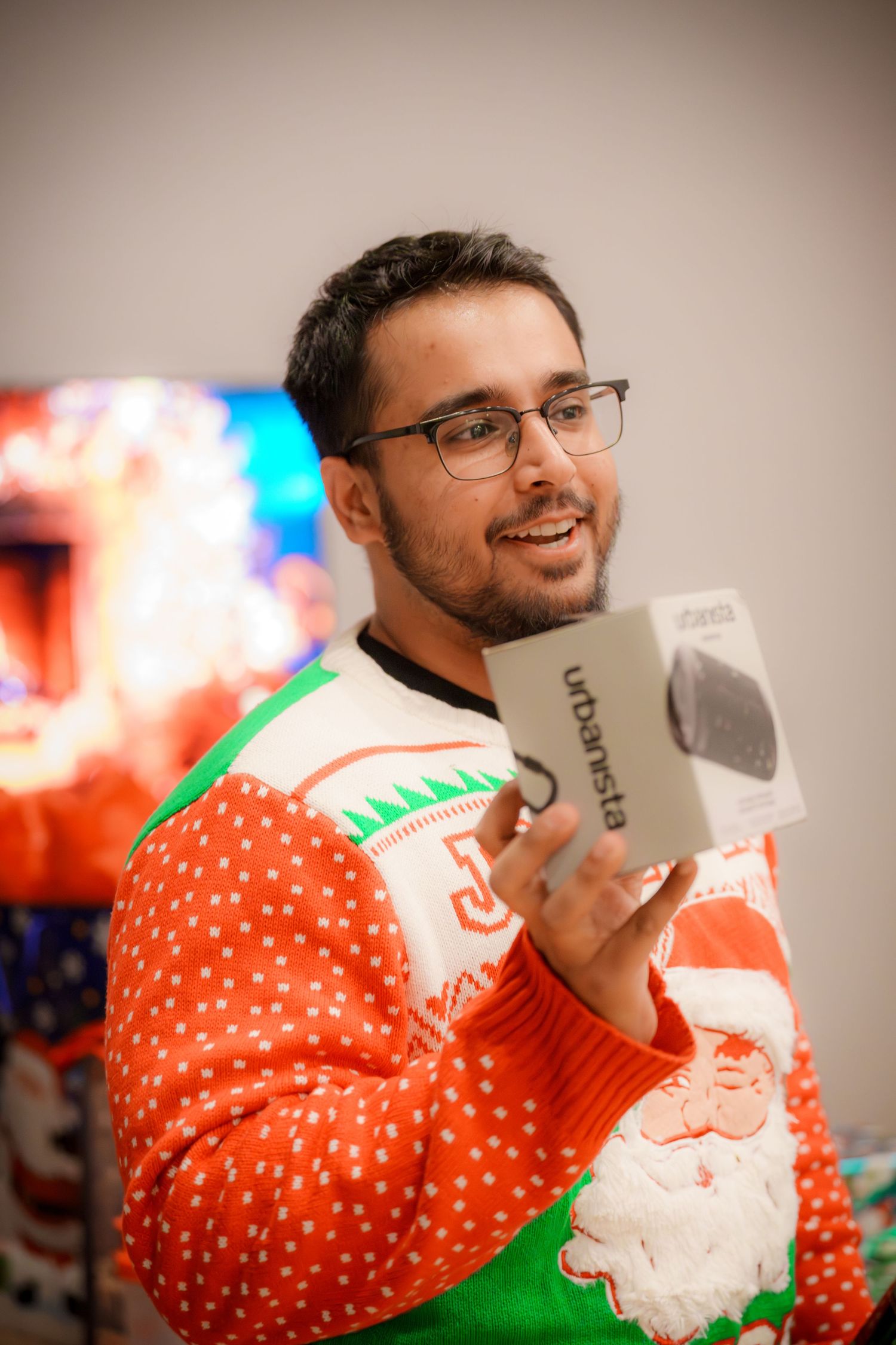 Person wearing festive Santa-themed holiday sweater at a party.