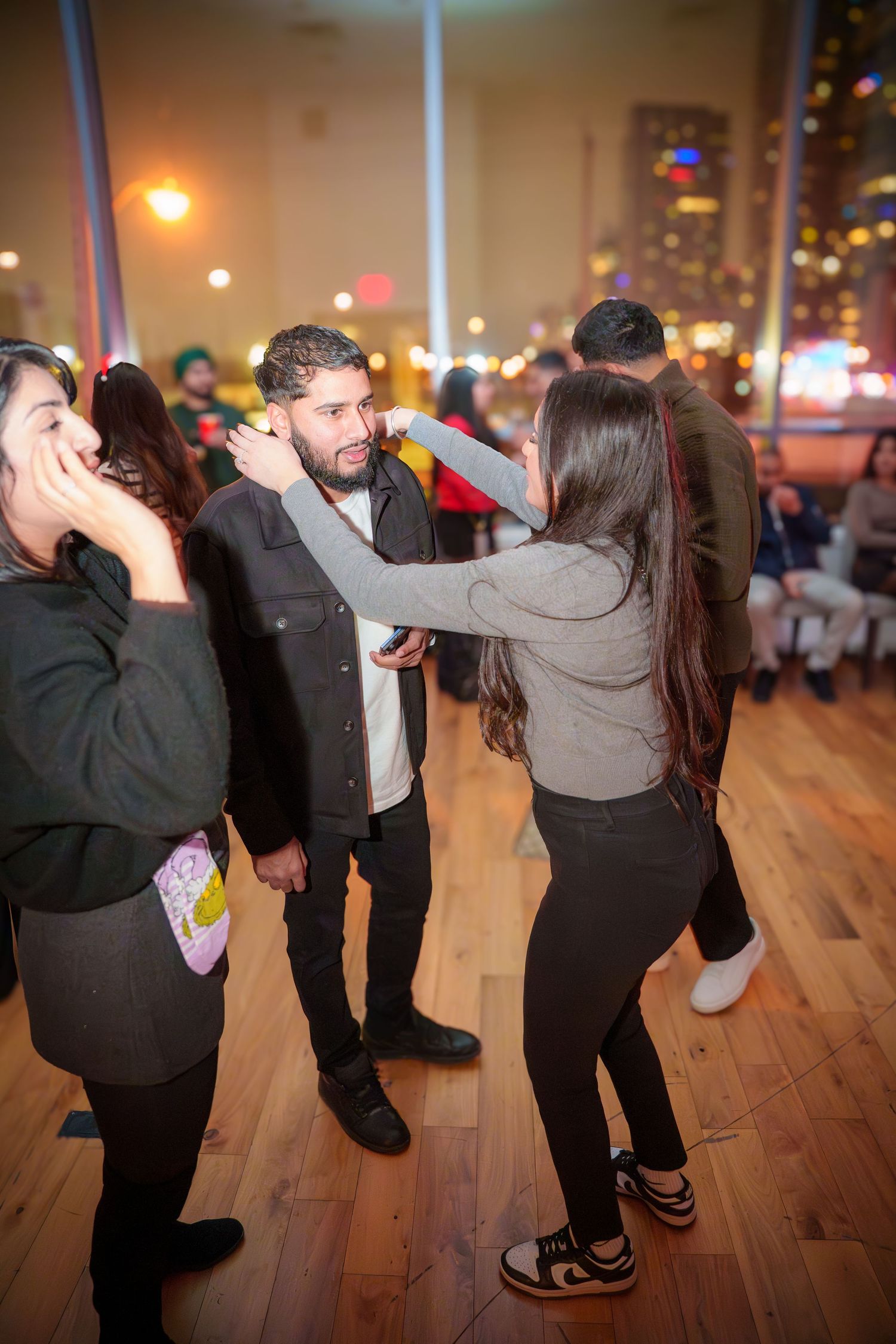 People dancing and socializing on a wooden floor at an indoor event.