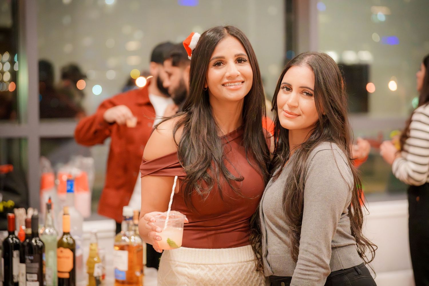 Friends socializing and enjoying drinks at evening party with festive lighting.