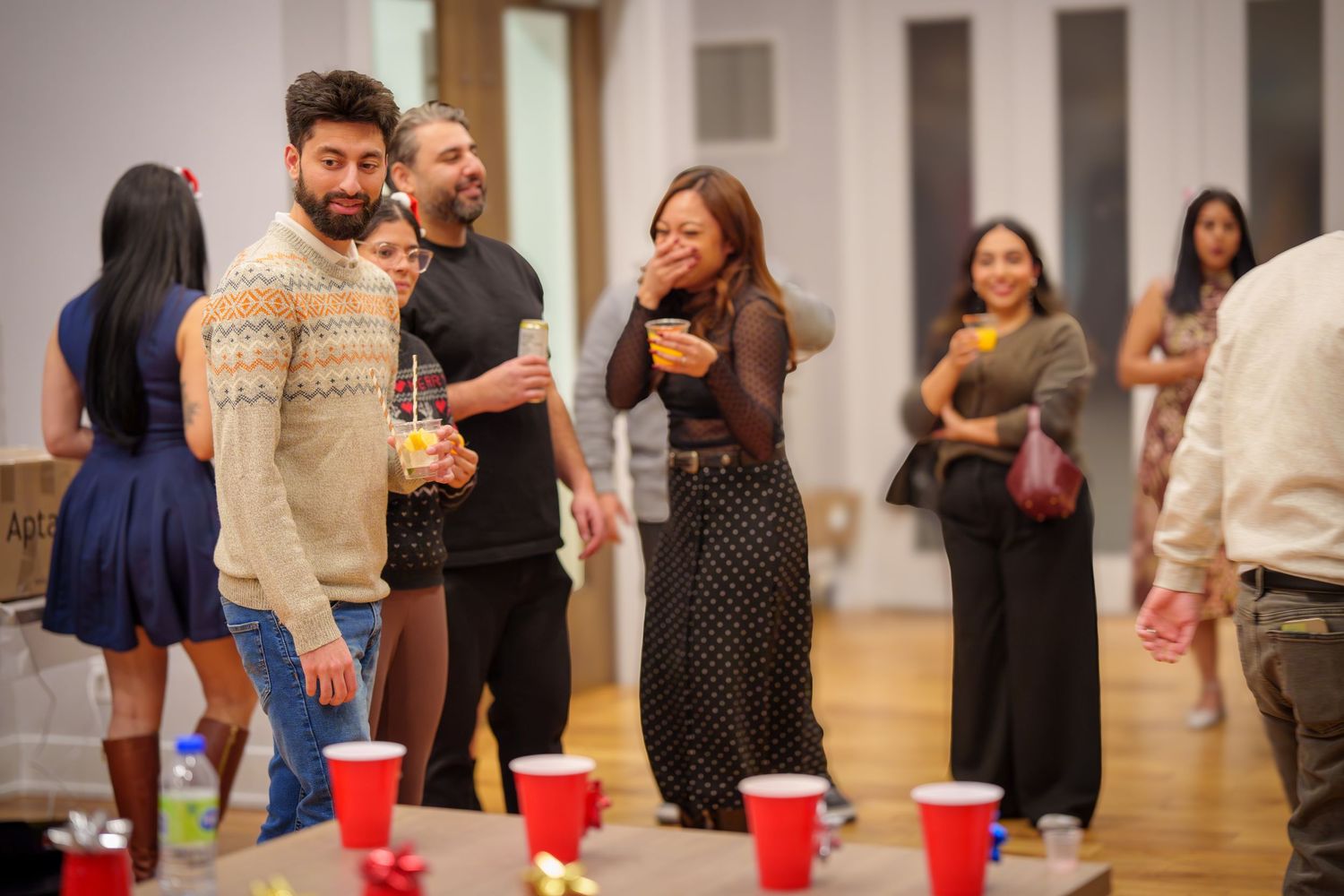 Group socializing at indoor gathering with decorative cup arrangement visible.