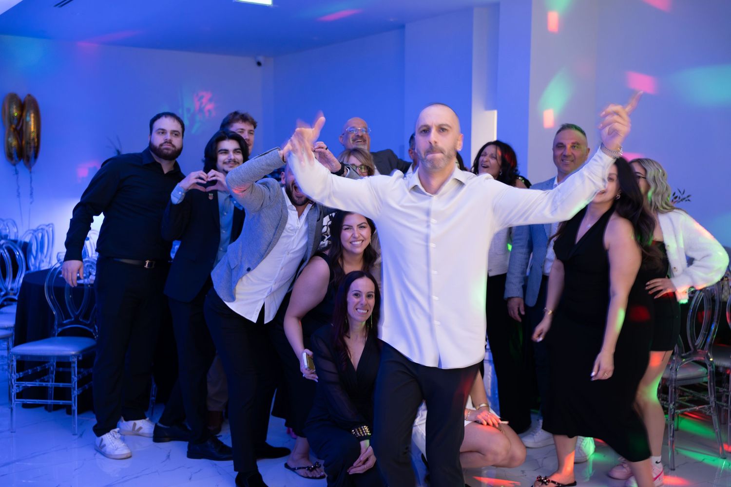 Party crowd dancing and celebrating in a venue with dramatic blue lighting effects.
