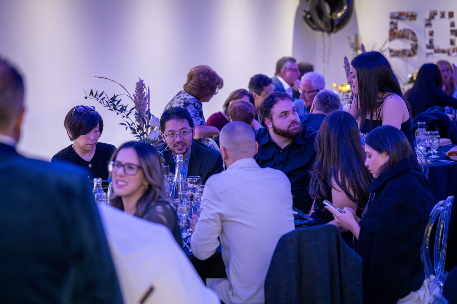 People socializing at an evening event with purple ambient lighting.