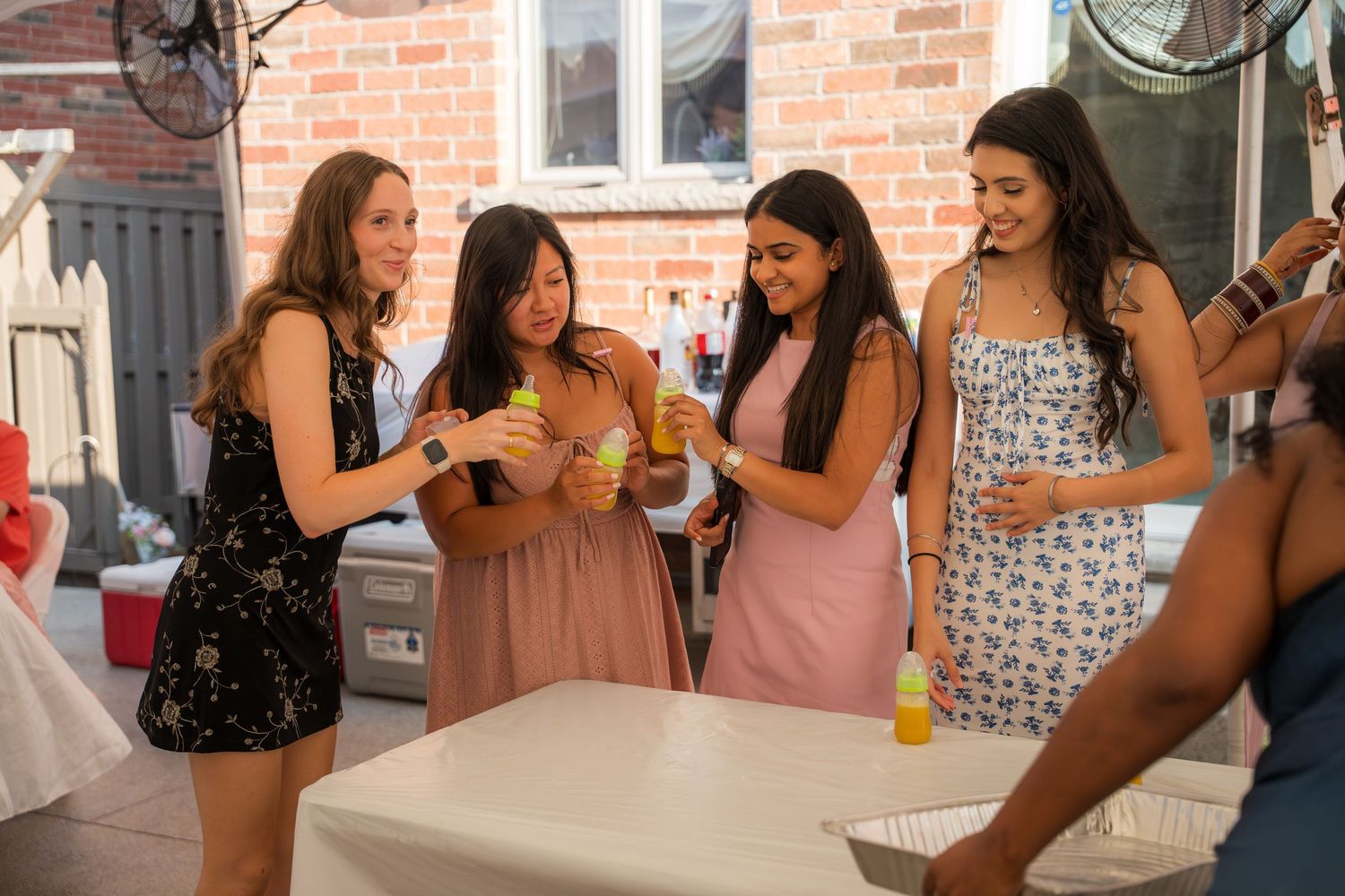 Friends in summer dresses socialize and laugh together at an indoor celebration.