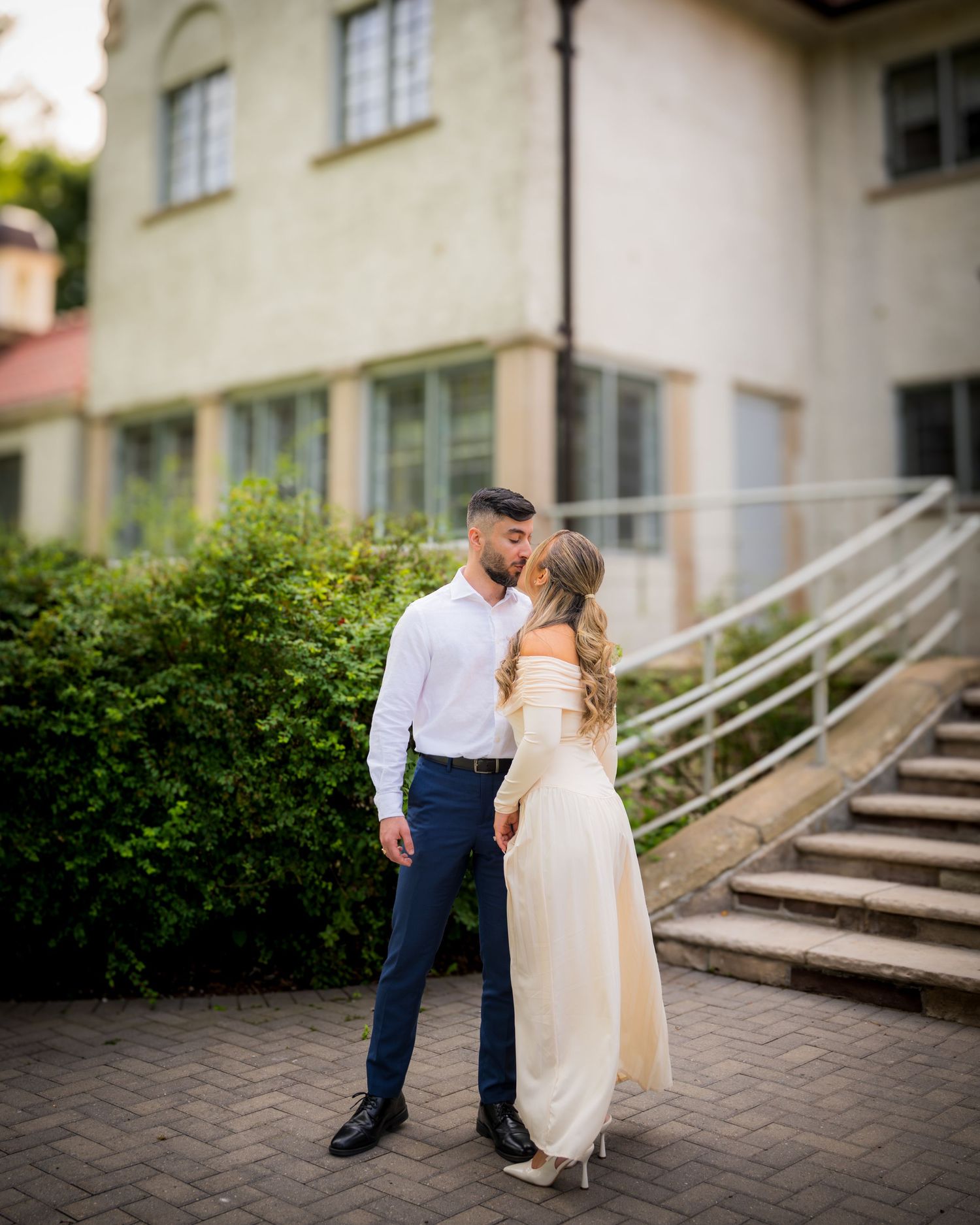 Elegant wedding couple on stone steps outside historic white building.