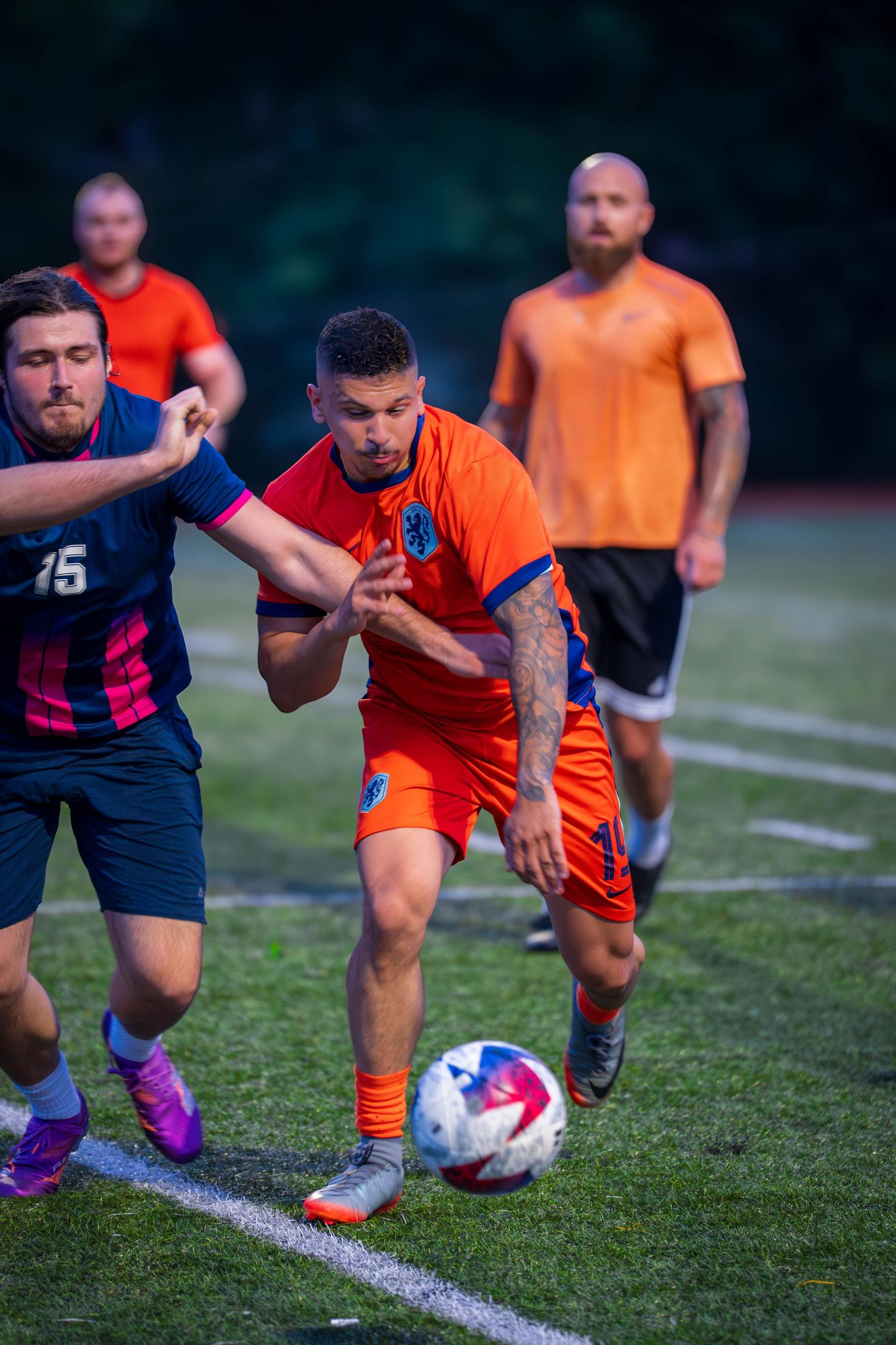 Players from opposing teams compete for possession during soccer match.